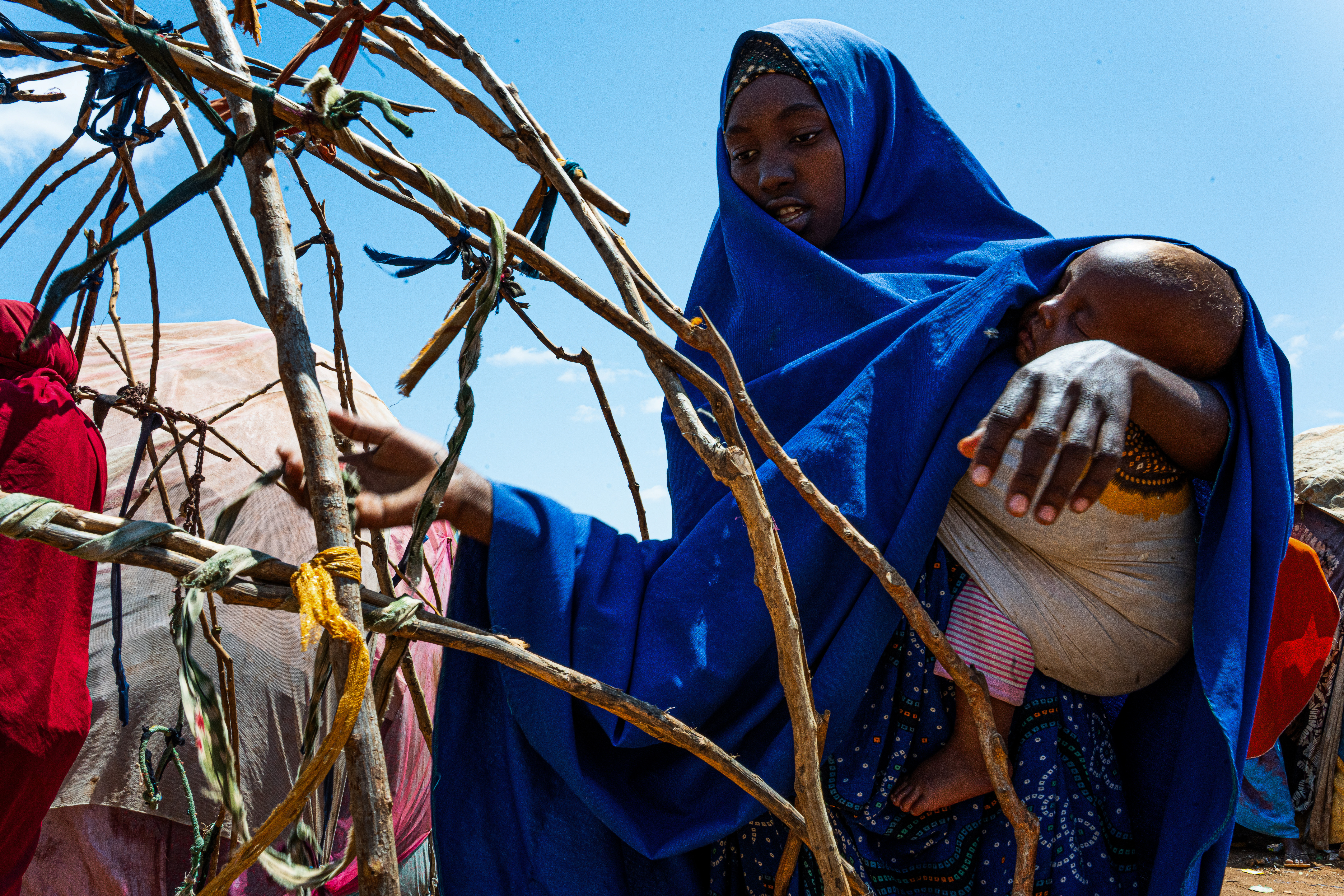 Farhiya Abdullahi Derow, 20, fled El Berde after losing all her livestock, her main source of income. Her husband disappeared during the crisis and she still does not know his whereabouts. On the journey to Baidoa, she and her children survived by stopping along the road to eat wild roots. She arrived at Qaydar-adde camp exhausted and with nothing. "We need food, my children have nothing to eat," she says. "I go out to beg just to feed my children." Qaydar-adde displacement camp, Baidoa, Southwest State, Somalia. [Abdulkadir Mohamed/NRC]