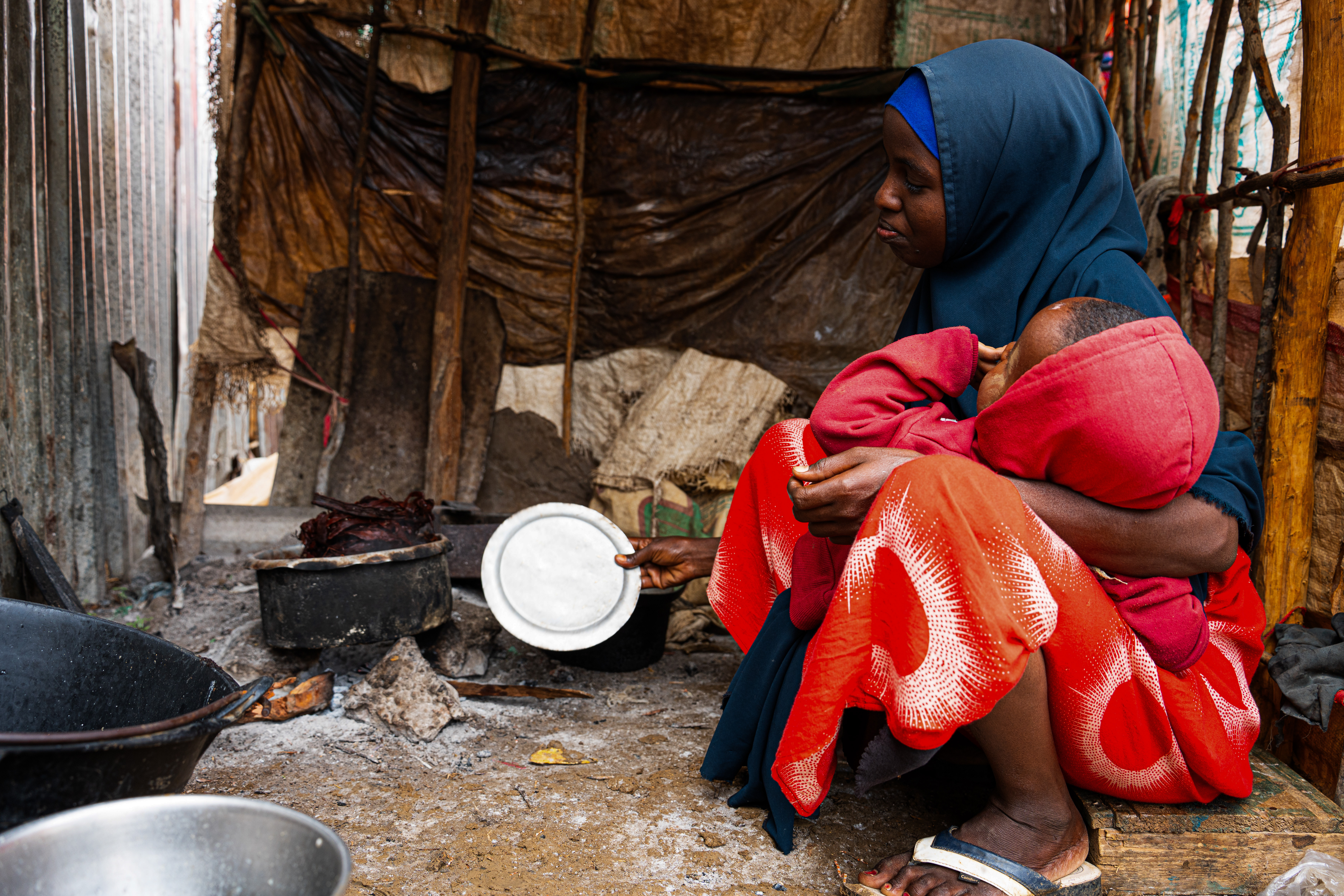 Farhia Isack is 28 and was displaced from the Bay region after the prolonged drought wiped out her rainfed farm and her livestock. Since arriving in Baidoa with her five children, she has received no income and no humanitarian assistance. Determined to keep her children alive, she walks to the outskirts of the city each day to collect branches from the Acacia tree, which she processes into a crude form of broth; the family's only source of nourishment. "I walk long distances under the sun just to find these trees," she says. "My children cry from hunger, and I have no answer for them. I am doing everything I can, but I cannot do this alone." Baidoa, Southwest State, Somalia. [Abdulkadir Mohamed/NRC]