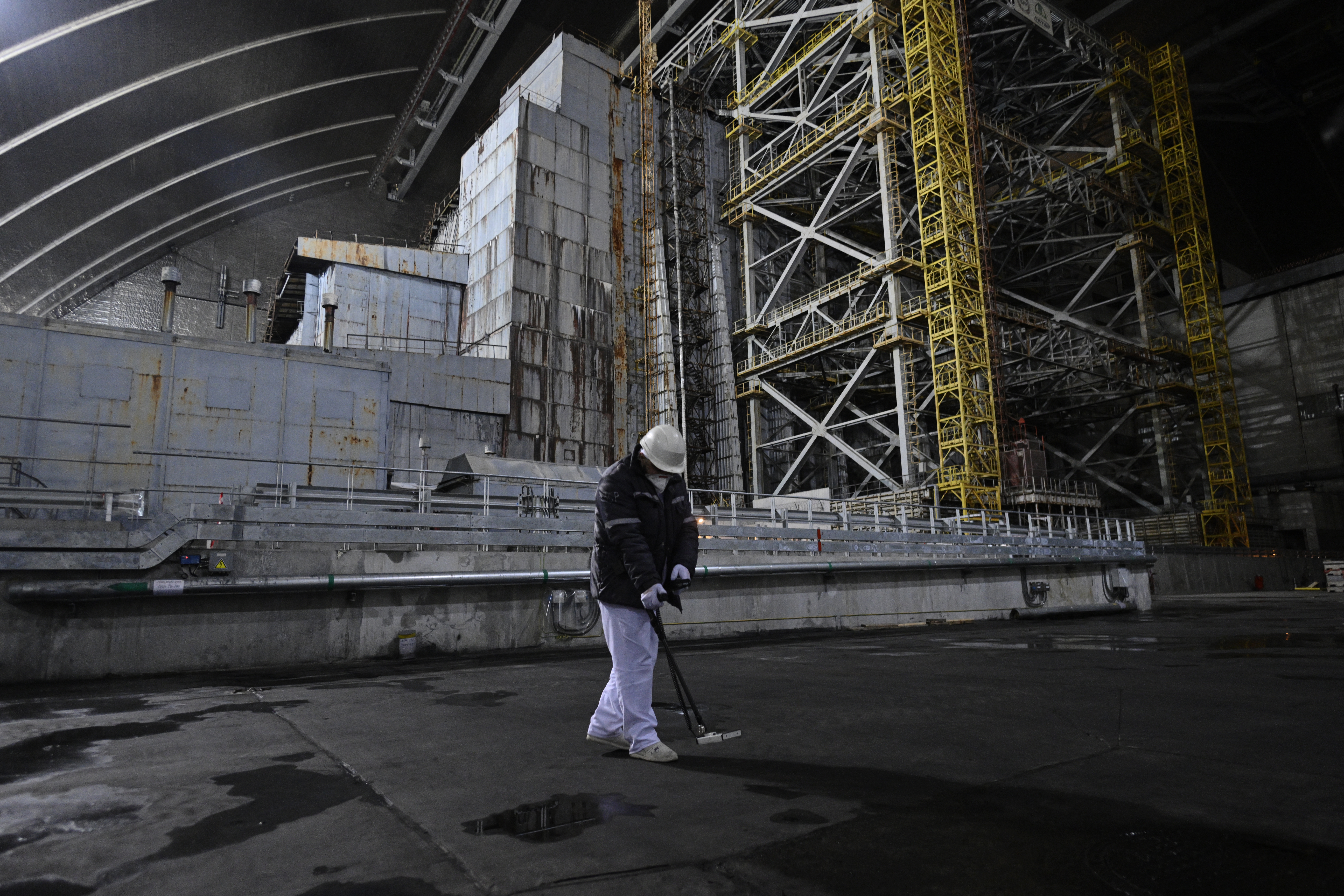 A radiation protection engineer works in front of the sarcophagus covering the destroyed fourth reactor under the New Safe Confinement (NSC), at the Chornobyl Nuclear Power Plant on April 9, 2026, amid the Russian invasion of Ukraine.