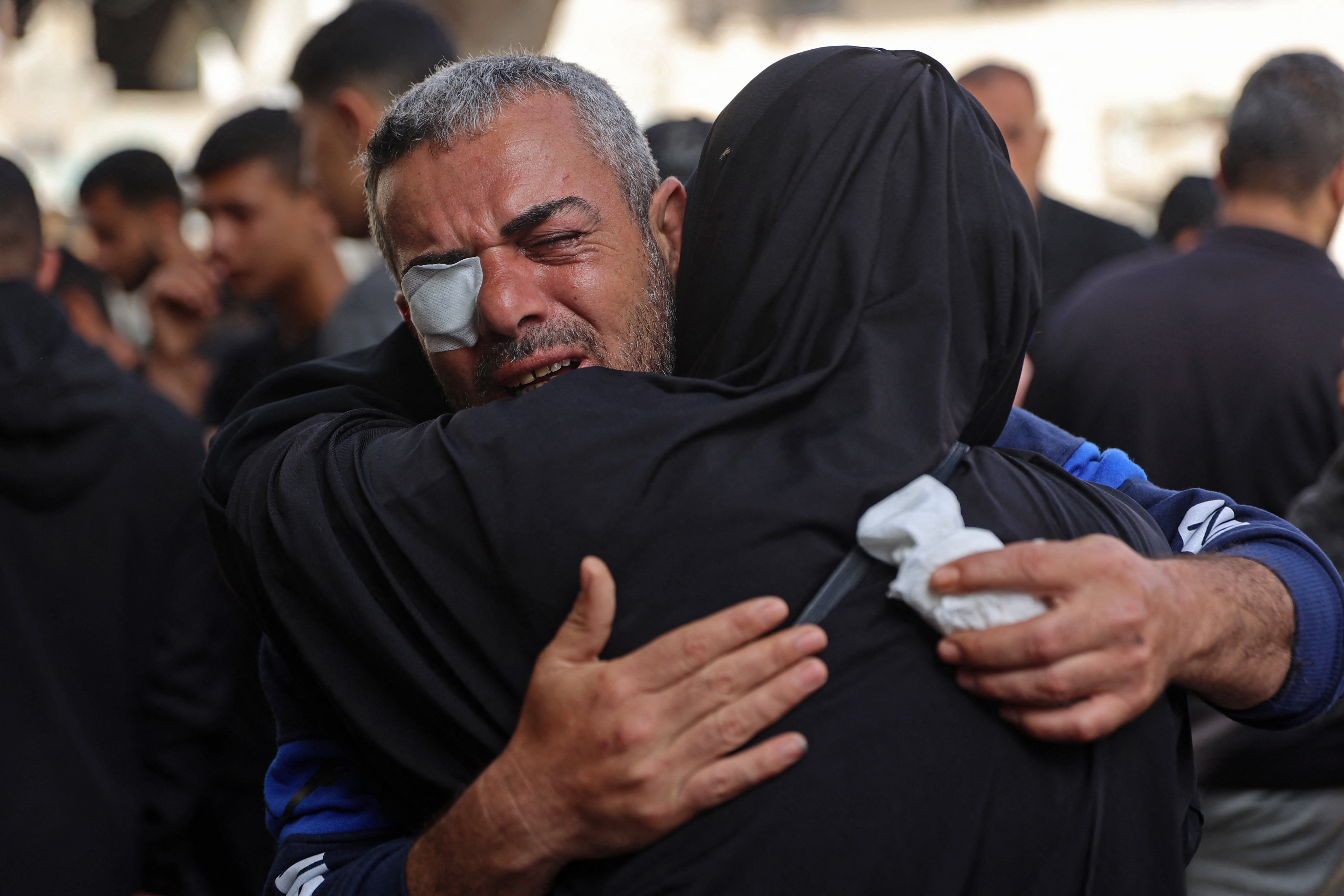 Mourners weep near the bodies of a woman and her two children at a hospital in Gaza City