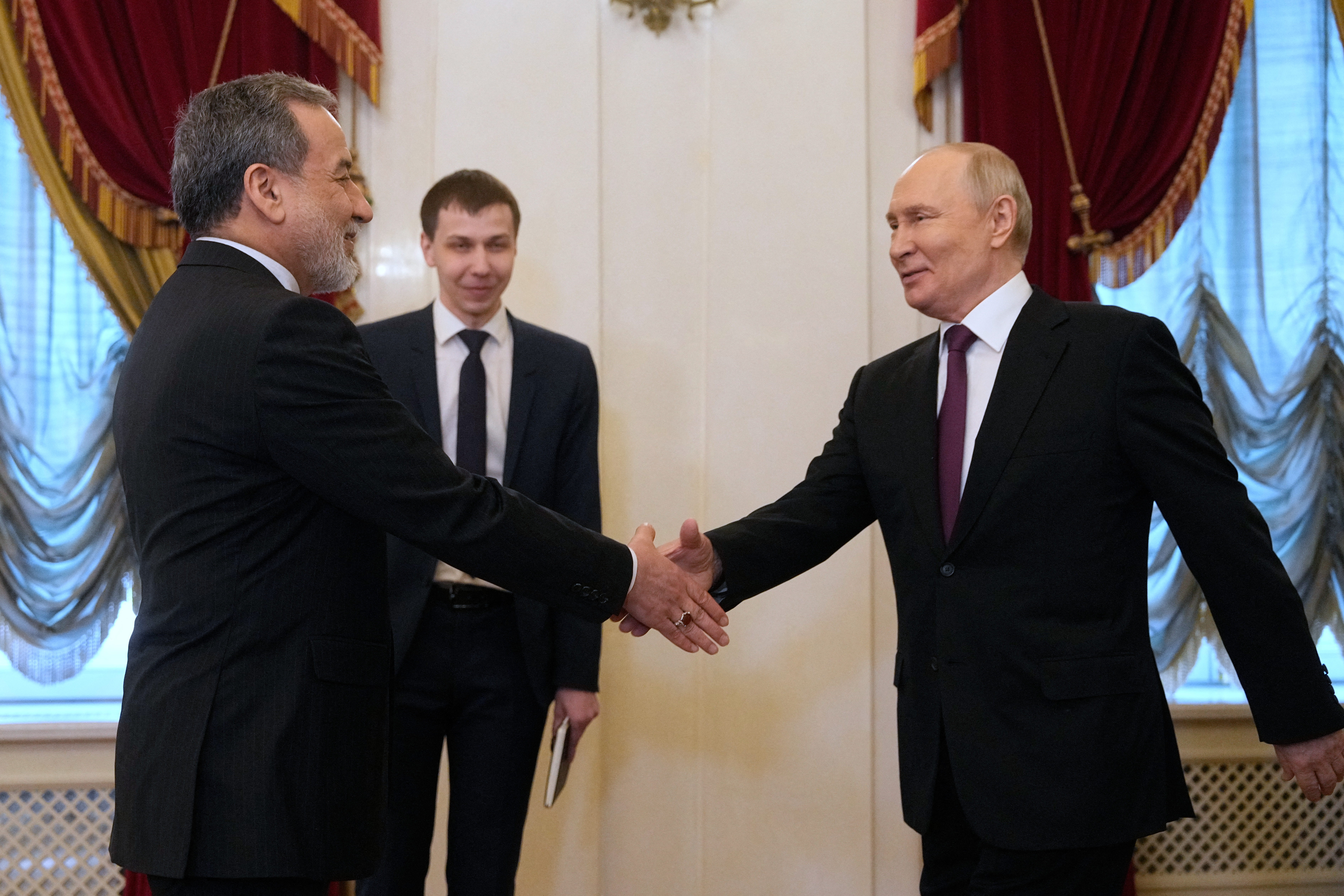 TOPSHOT - Russian President Vladimir Putin shakes hands with Iranian Foreign Minister Abbas Araghchi during their meeting at the Boris Yeltsin Presidential Library in Saint Petersburg on April 27, 2026. (Photo by Dmitry LOVETSKY / POOL / AFP)