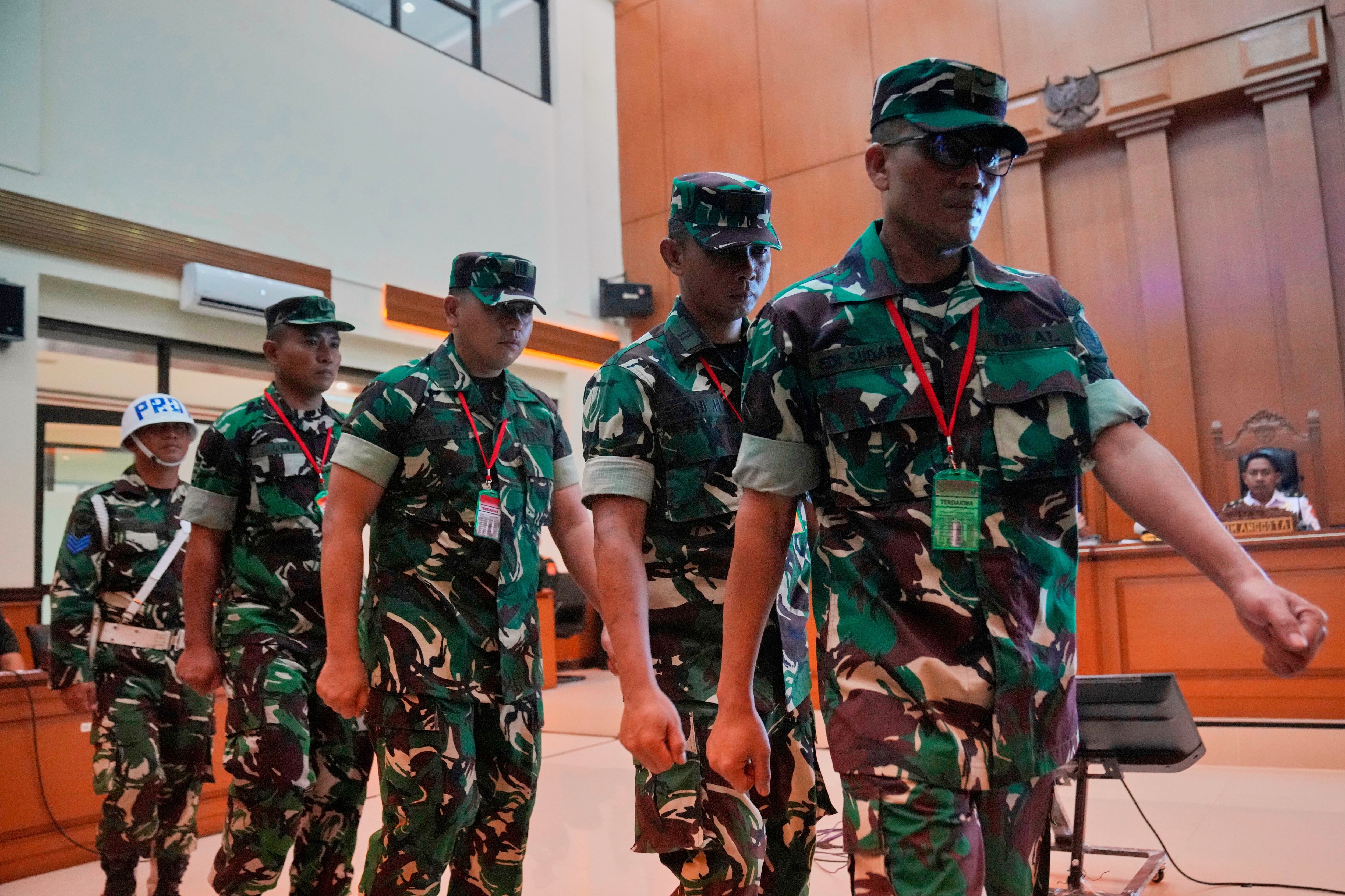 A military police person, far left, escorts Indonesian military personnel in court.