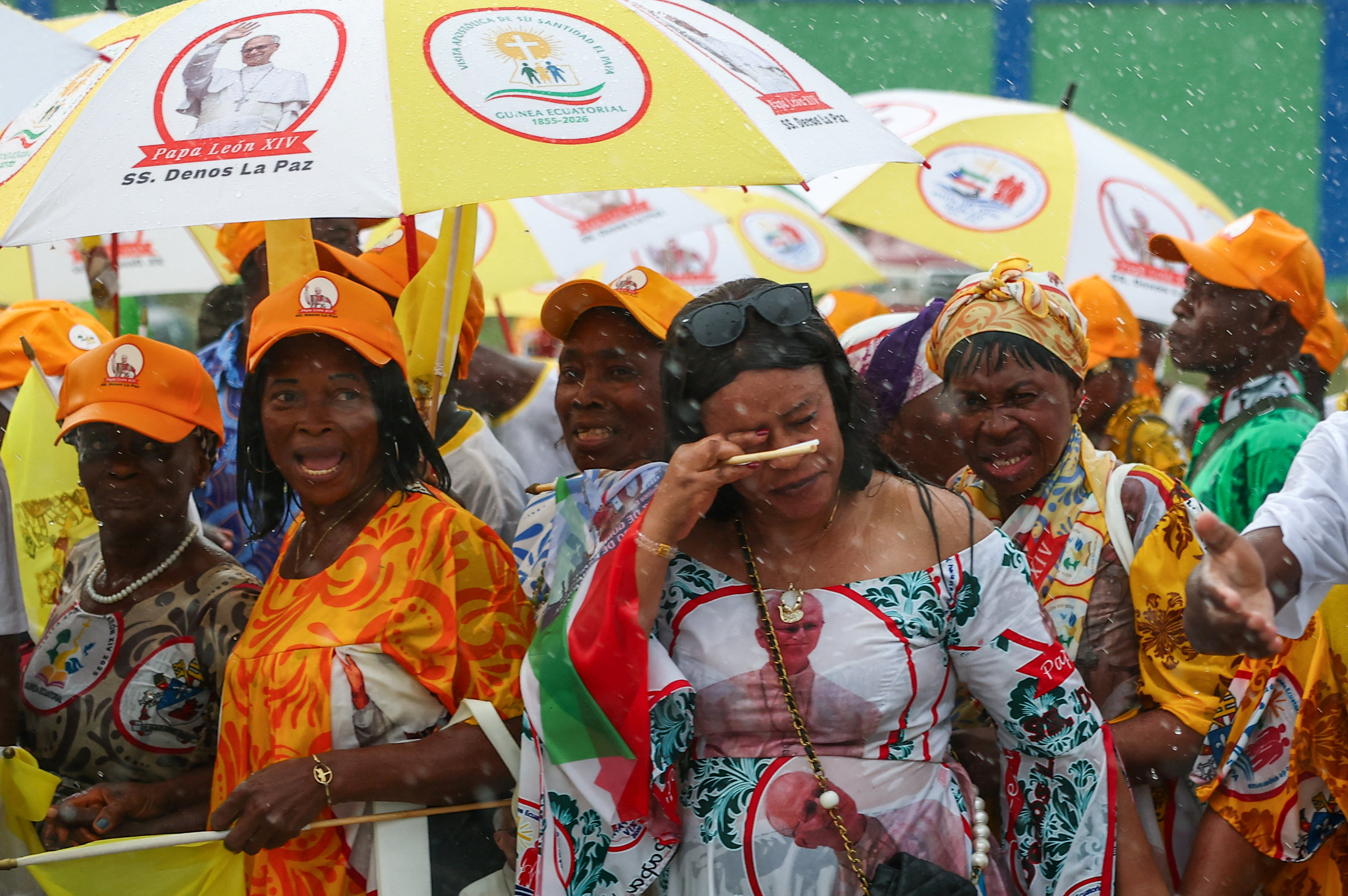 People use umbrellas to shelter from the rain as they wait on a street for Pope Leo XIV to pass by, in Bata, Equatorial Guinea, April 22, 2026. REUTERS/Guglielmo Mangiapane