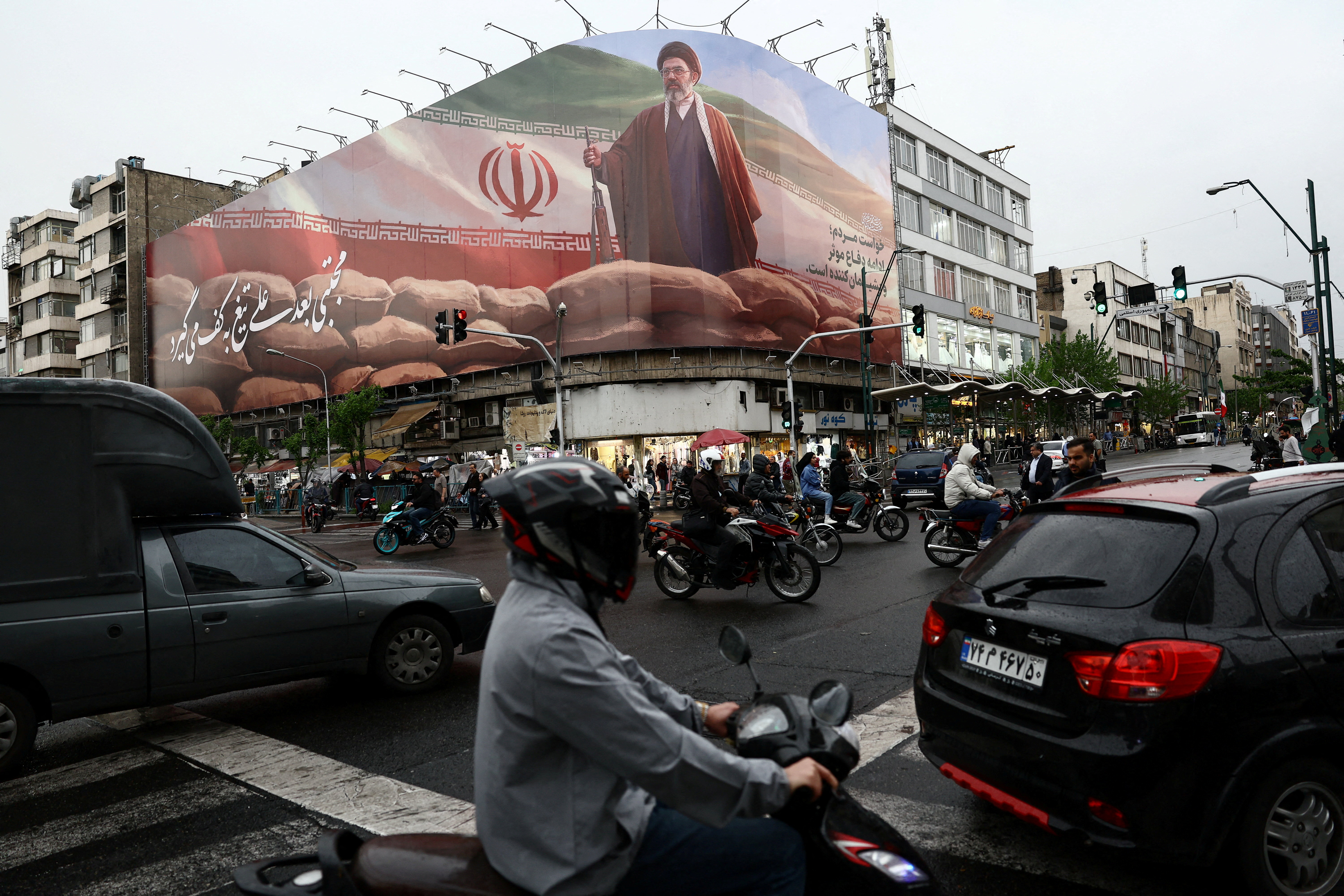 FILE PHOTO: People ride motorcycles near a billboard featuring an image of Iran's new Supreme Leader Mojtaba Khamenei, amid a ceasefire between U.S. and Iran, in Tehran, Iran, April 20, 2026. Majid Asgaripour/WANA (West Asia News Agency) via REUTERS ATTENTION EDITORS - THIS PICTURE WAS PROVIDED BY A THIRD PARTY/File Photo