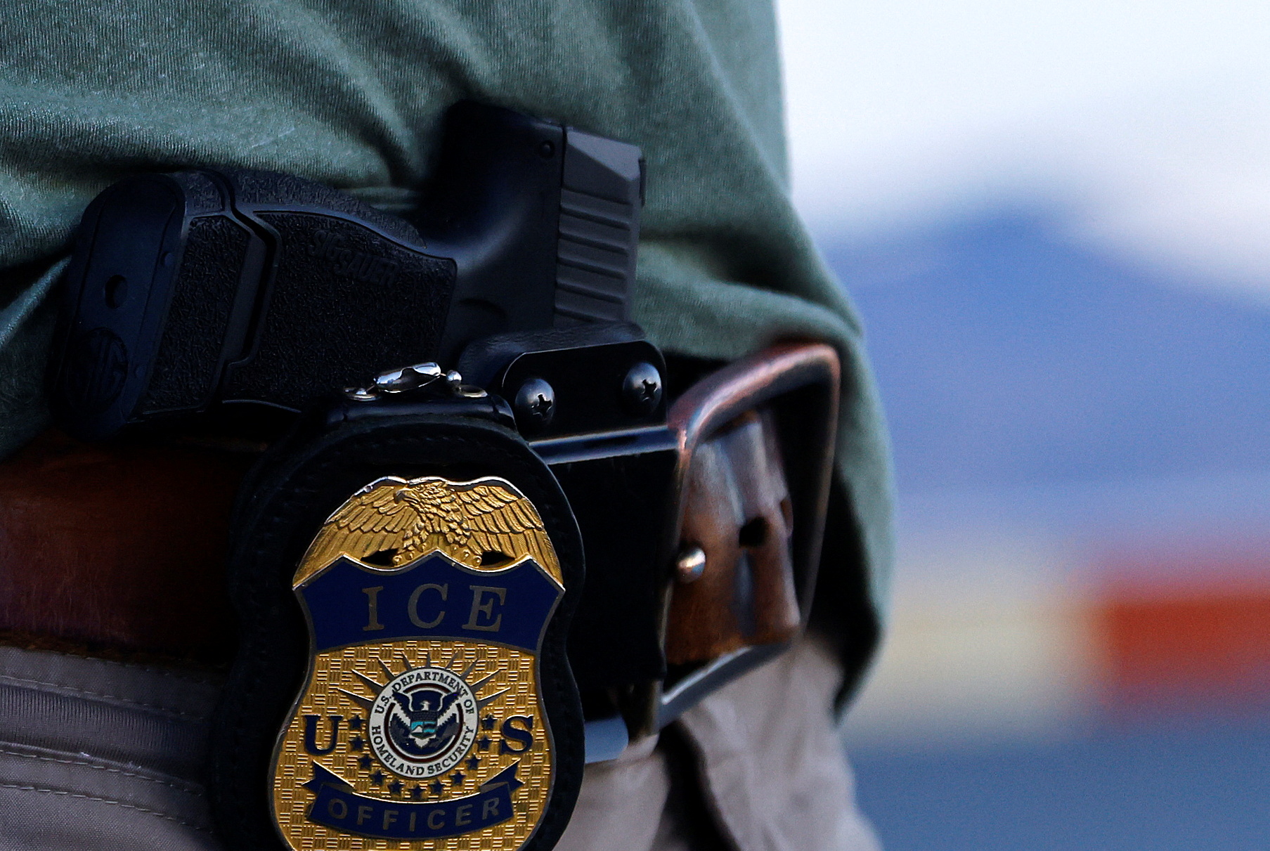 The badge of a U.S. Immigration and Customs Enforcement (ICE) agent is seen during an operation with migrants being transferred to a plane to be expelled under US