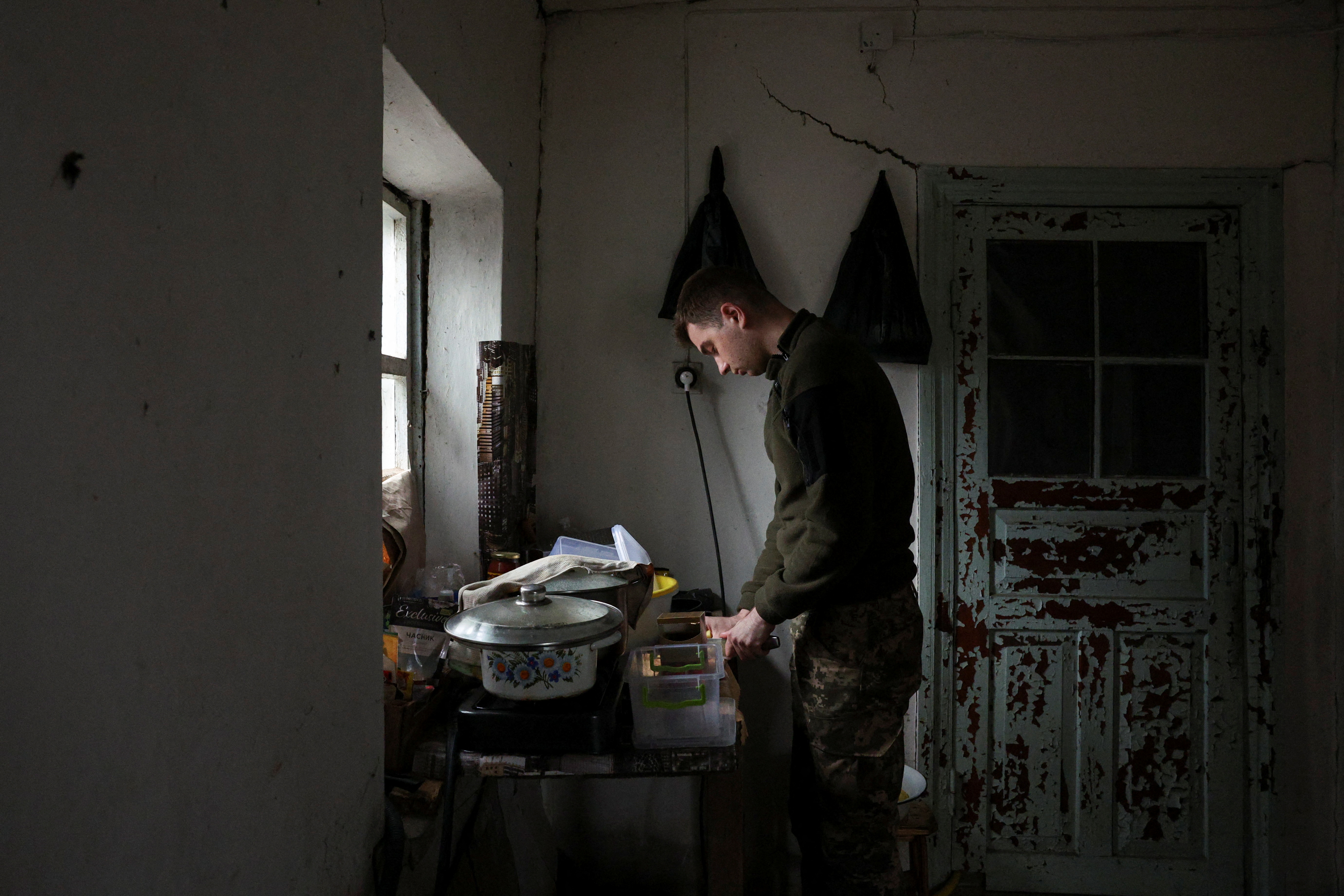 A soldier of the 59th Assault Brigade on rotation out of the eastern combat zone cooks food at a resting house during a five-day leave in the rear of the frontlines at an undisclosed location in the Dnipropetrovsk region before returning to the Pokrovsk defence effort, amid Russia's attack on Ukraine, Ukraine April 1, 2025. REUTERS/Violeta Santos Moura