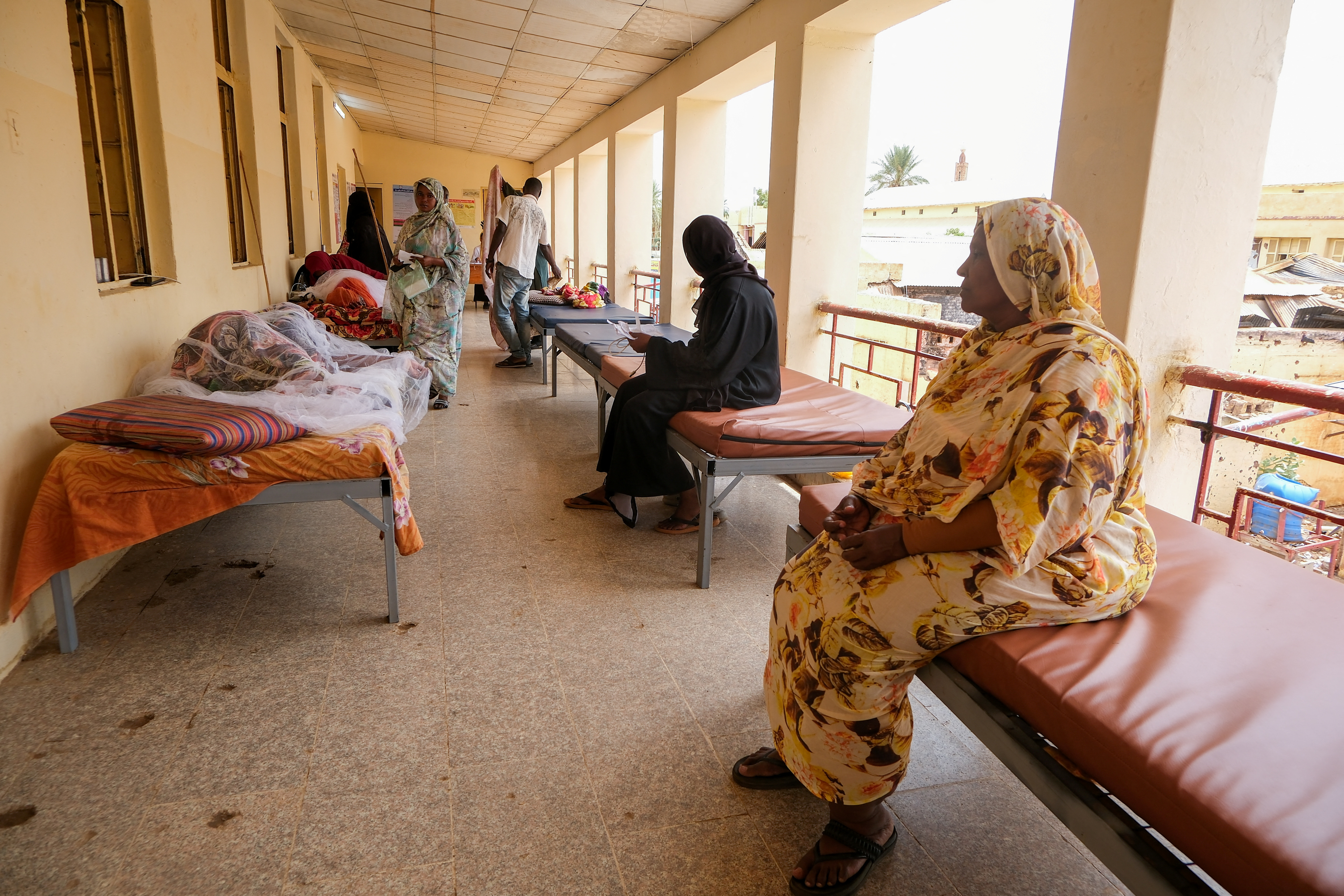 Sudanese women sit on beds while monitoring their family members at a hospital.