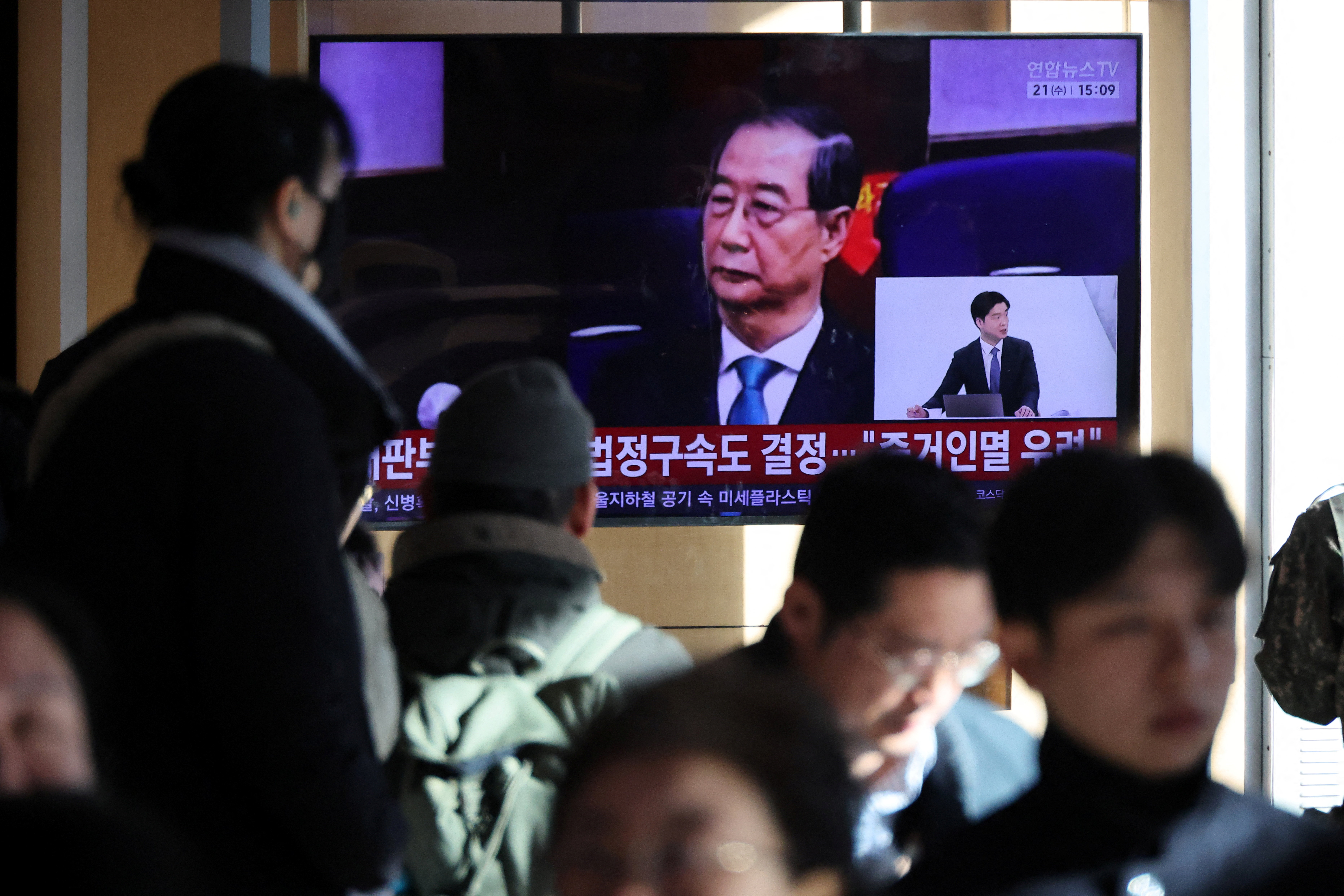People watch a TV broadcasting a news report on South Korea's Seoul Central District Court ruling on charges against former Prime Minister Han Duck-soo for engaging in a key action of insurrection concerning ex-President Yoon Suk Yeol's declaration of martial law in December 2024, in Seoul, South Korea, January 21, 2026.