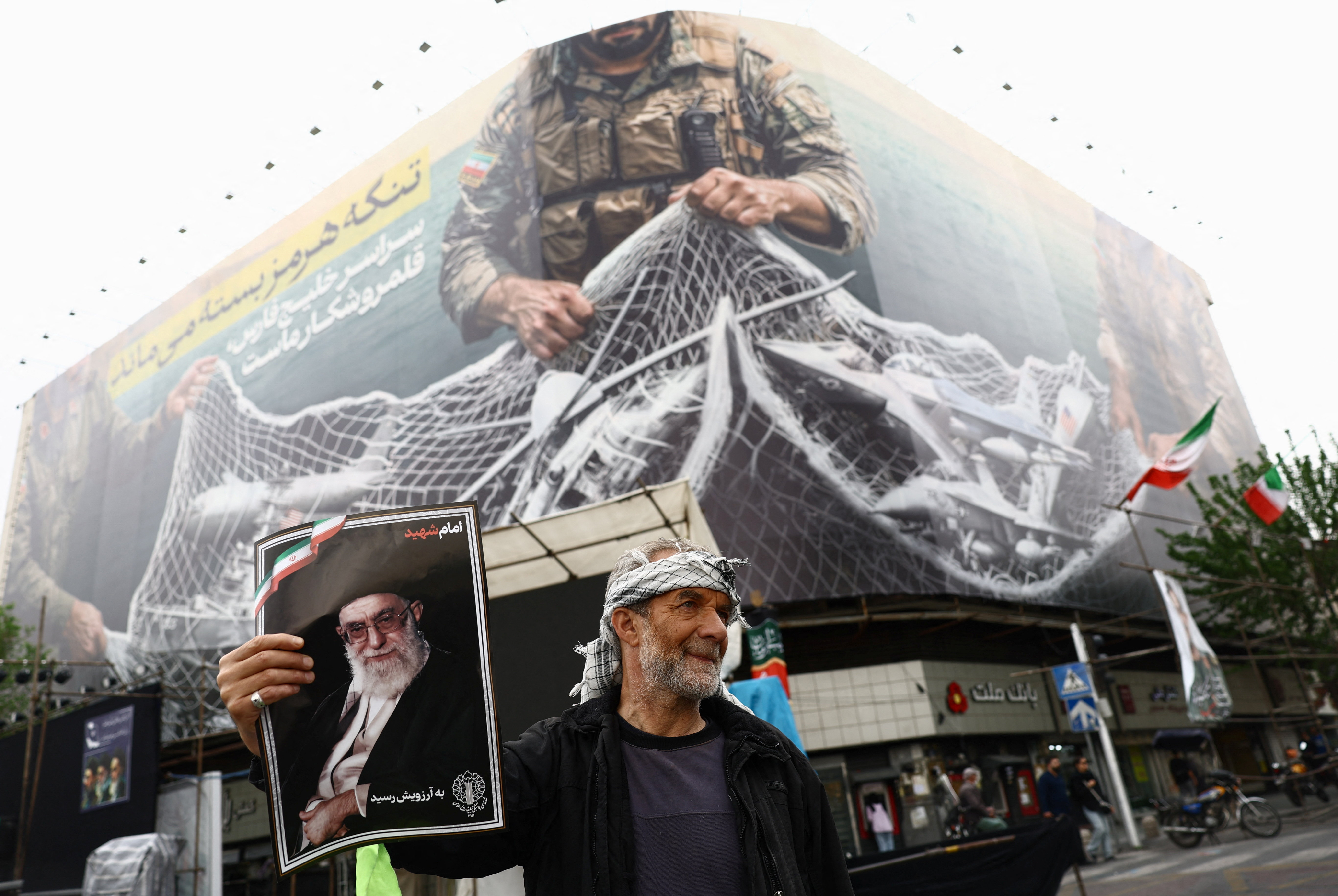 A man holds a picture of the late Supreme Leader of Iran Ayatollah Ali Khamenei,