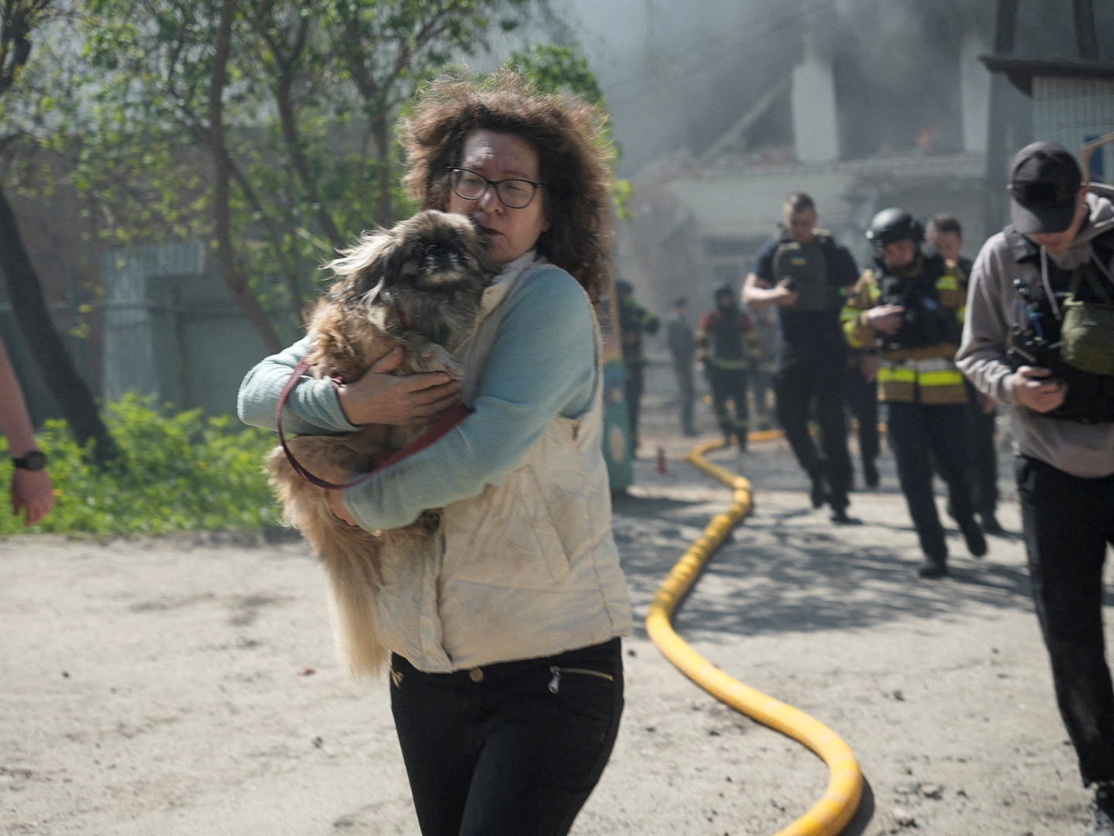 A resident with a dog and rescuers run during an air raid alarm.