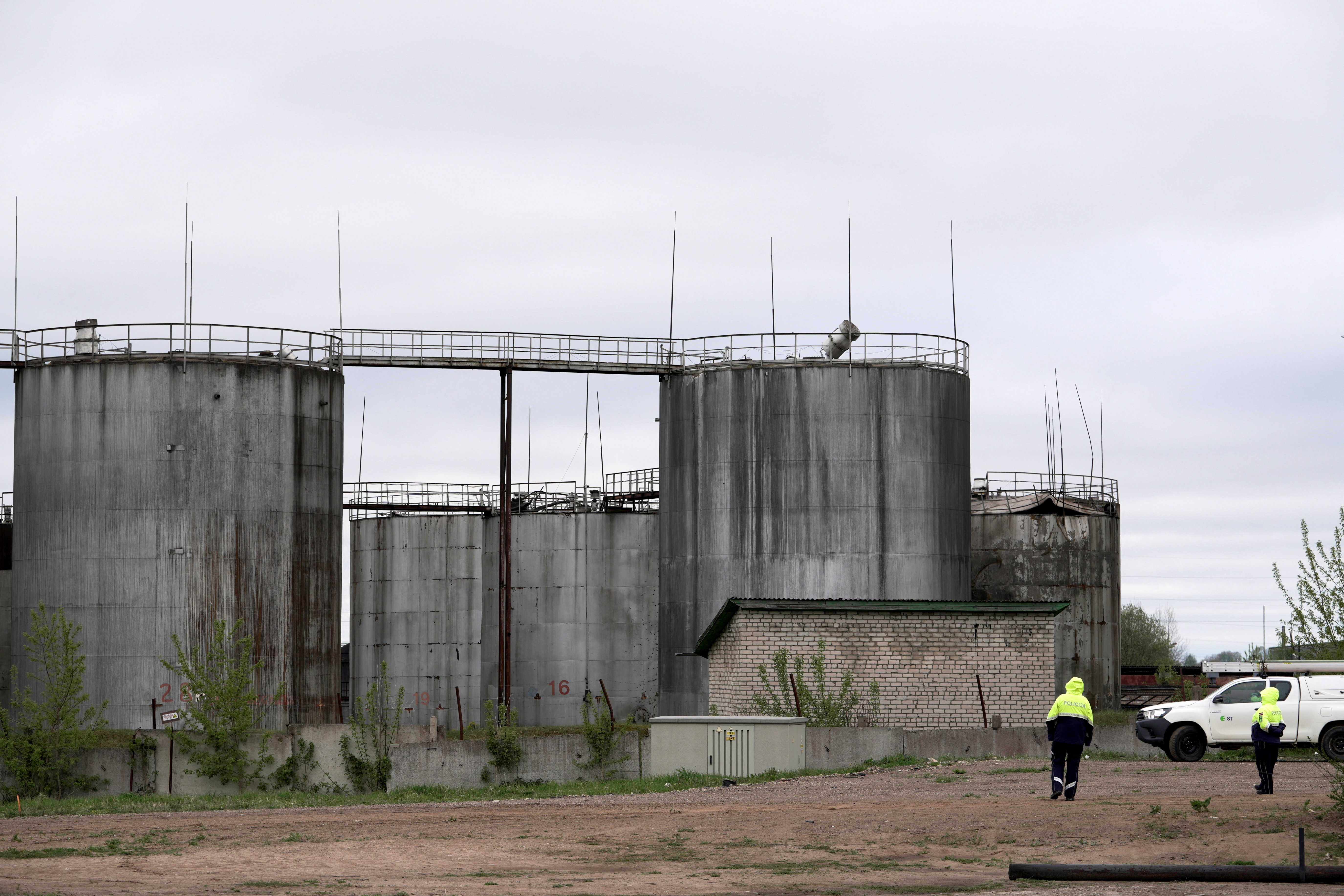 Police officers stand at the site of damage after drones crashed at a storage facility in Rezekne, Latvia, May 7, 2026. REUTERS/Janis Laizans