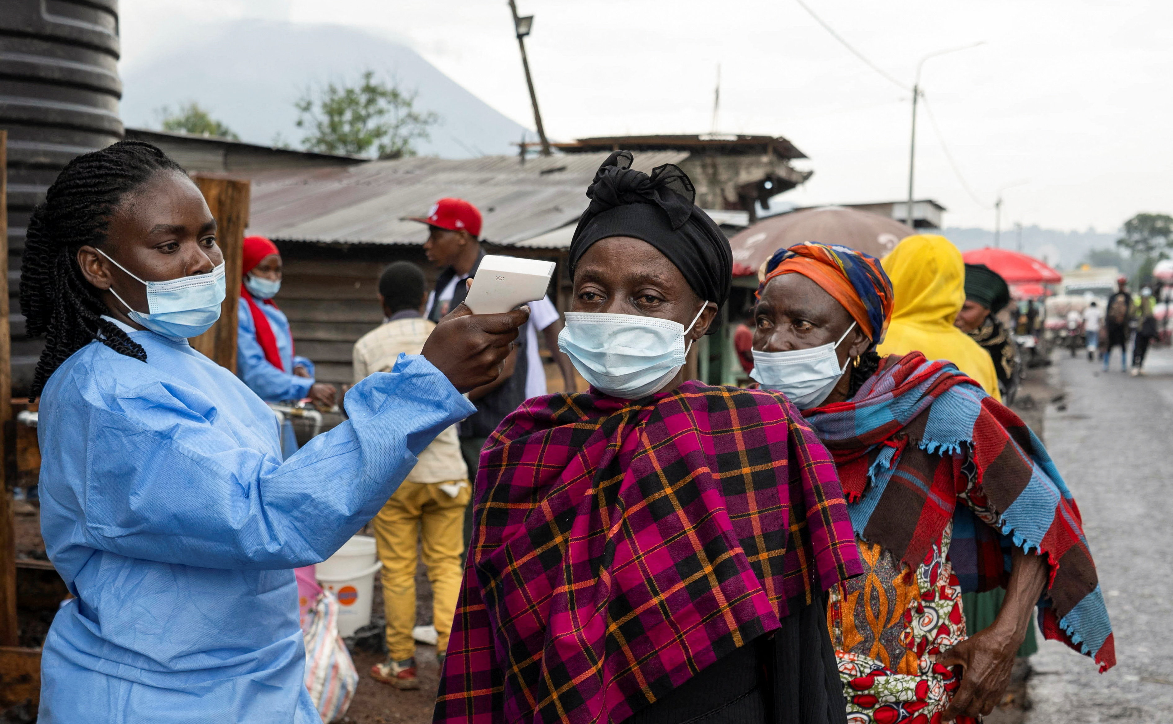 A health worker takes the temperature of a woman passing through the Kanyaruchinya checkpoint, DRC