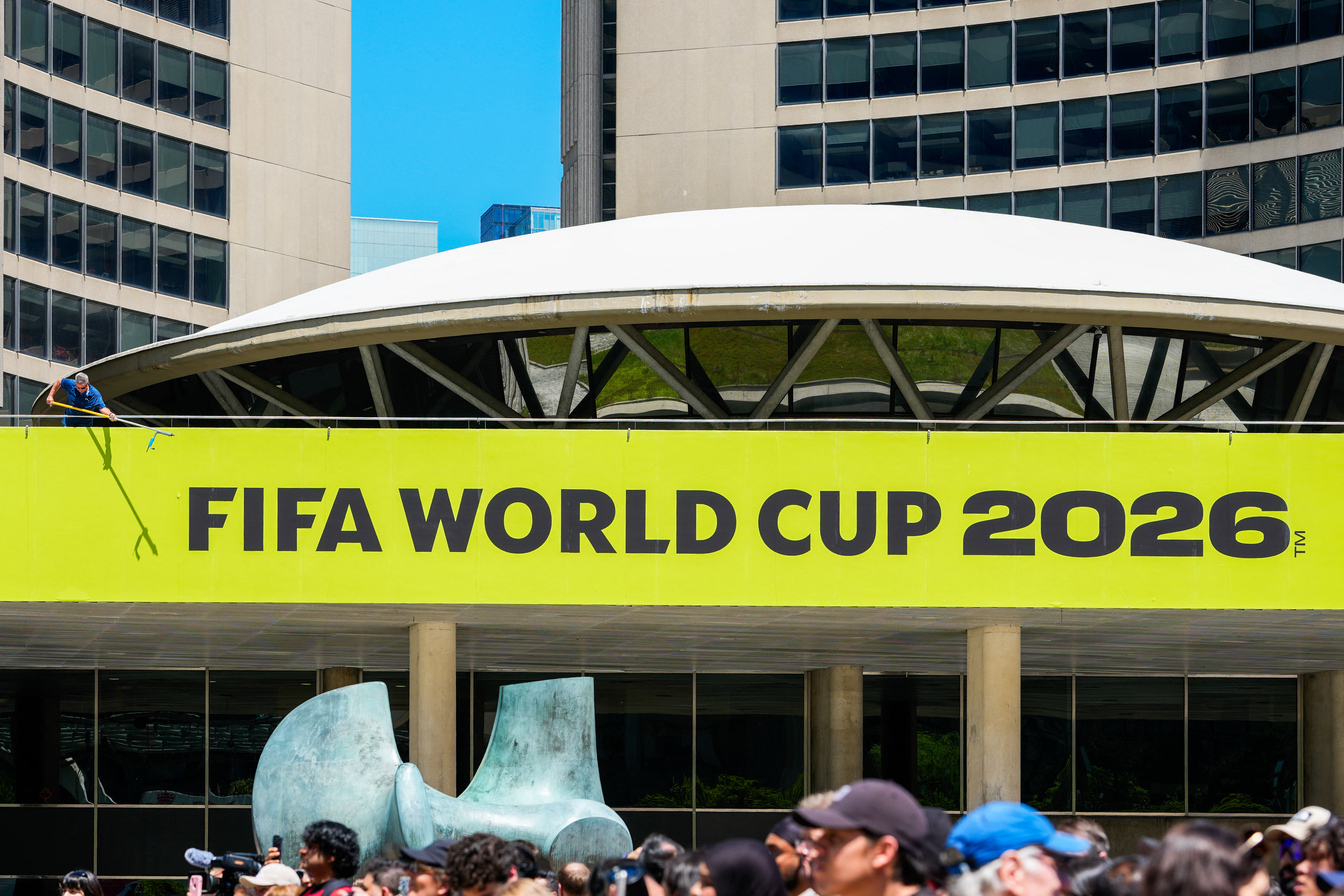 Toronto city worker cleans a sign outside of city hall during the FIFA World Cup Trophy Tour by Coca-Cola at Nathan Phillips Square