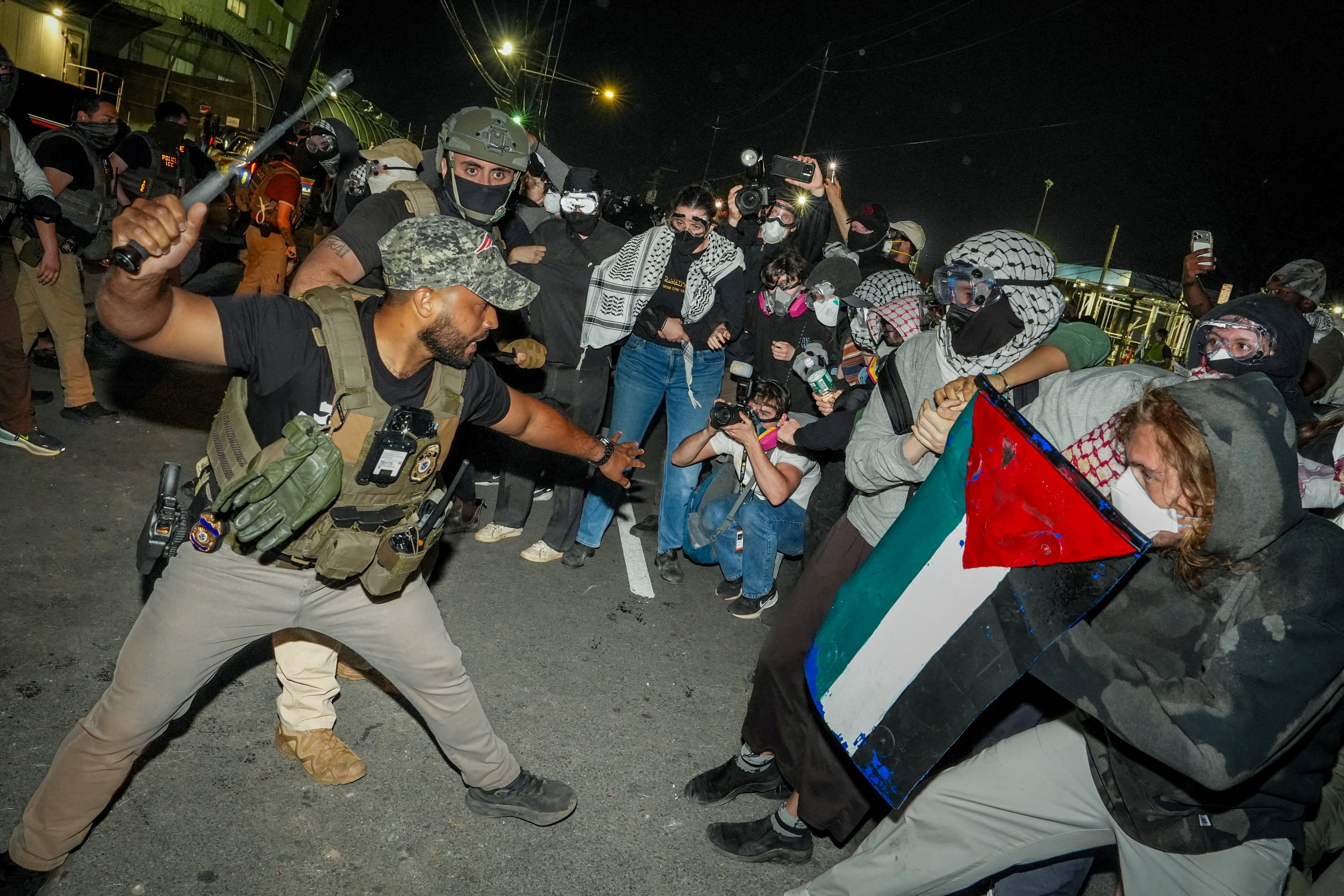 An ICE agent wields a baton against protesters