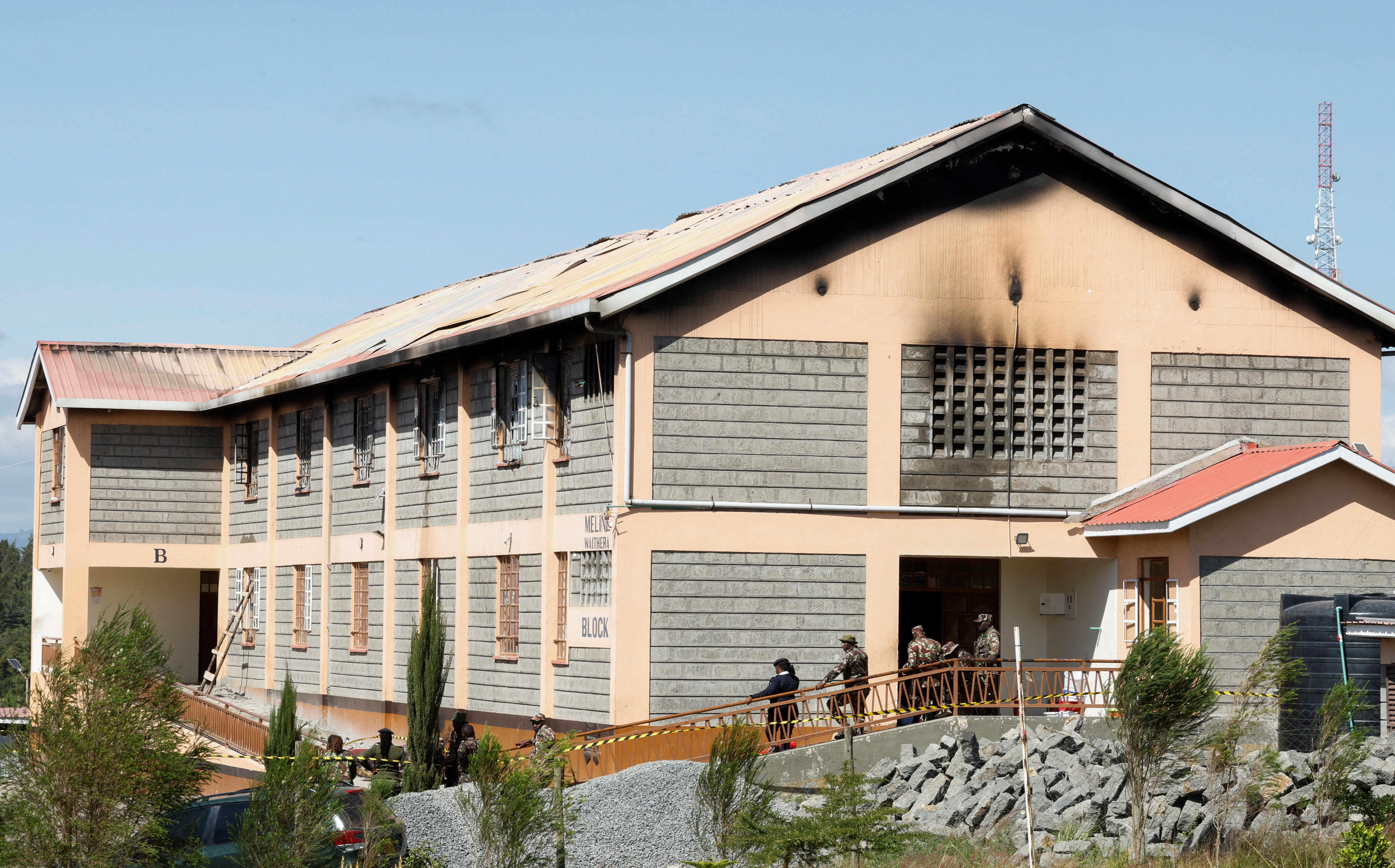 Security officers stand outside a burnt dormitory
