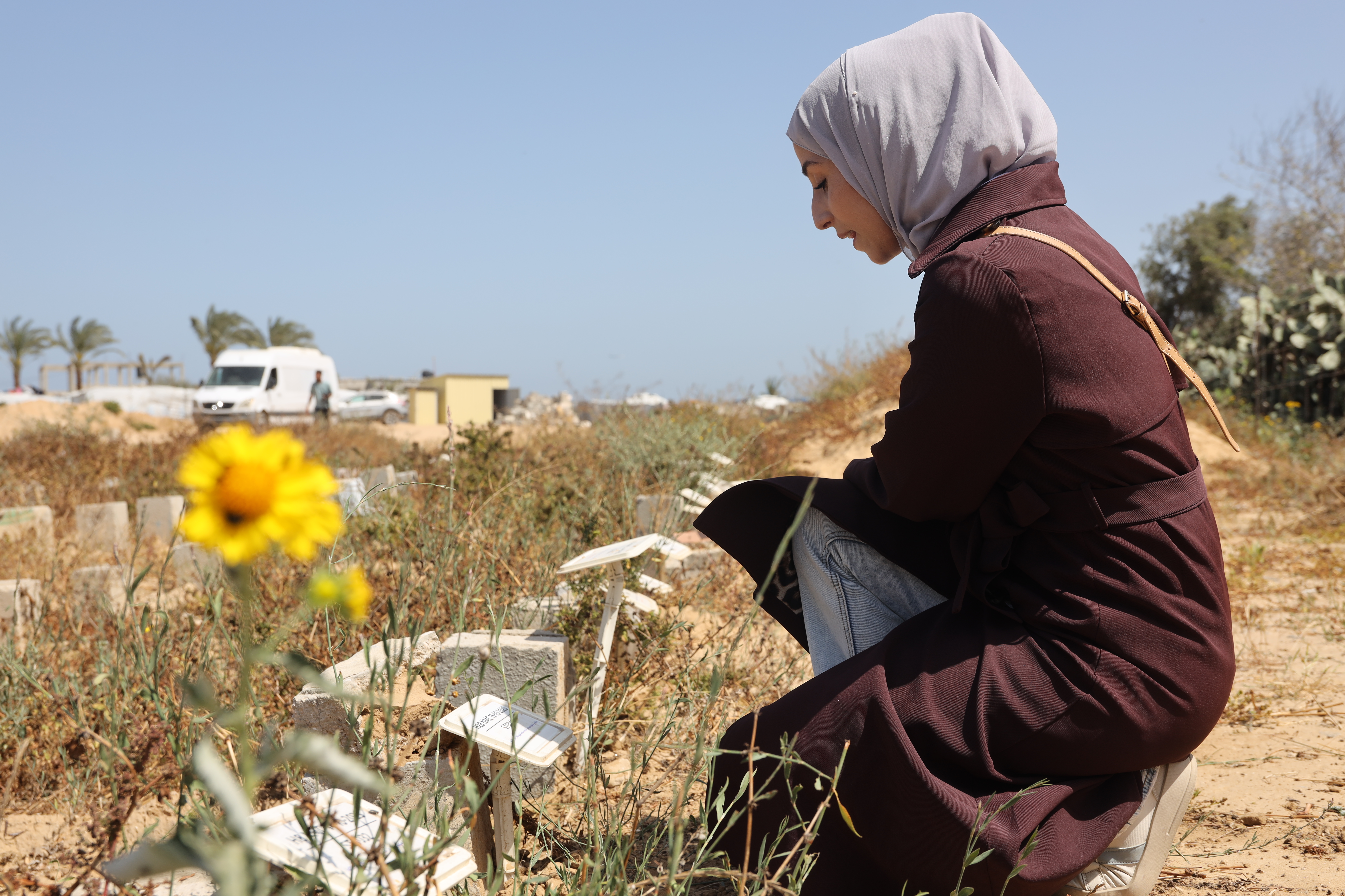 Woman kneels and stares at a grave