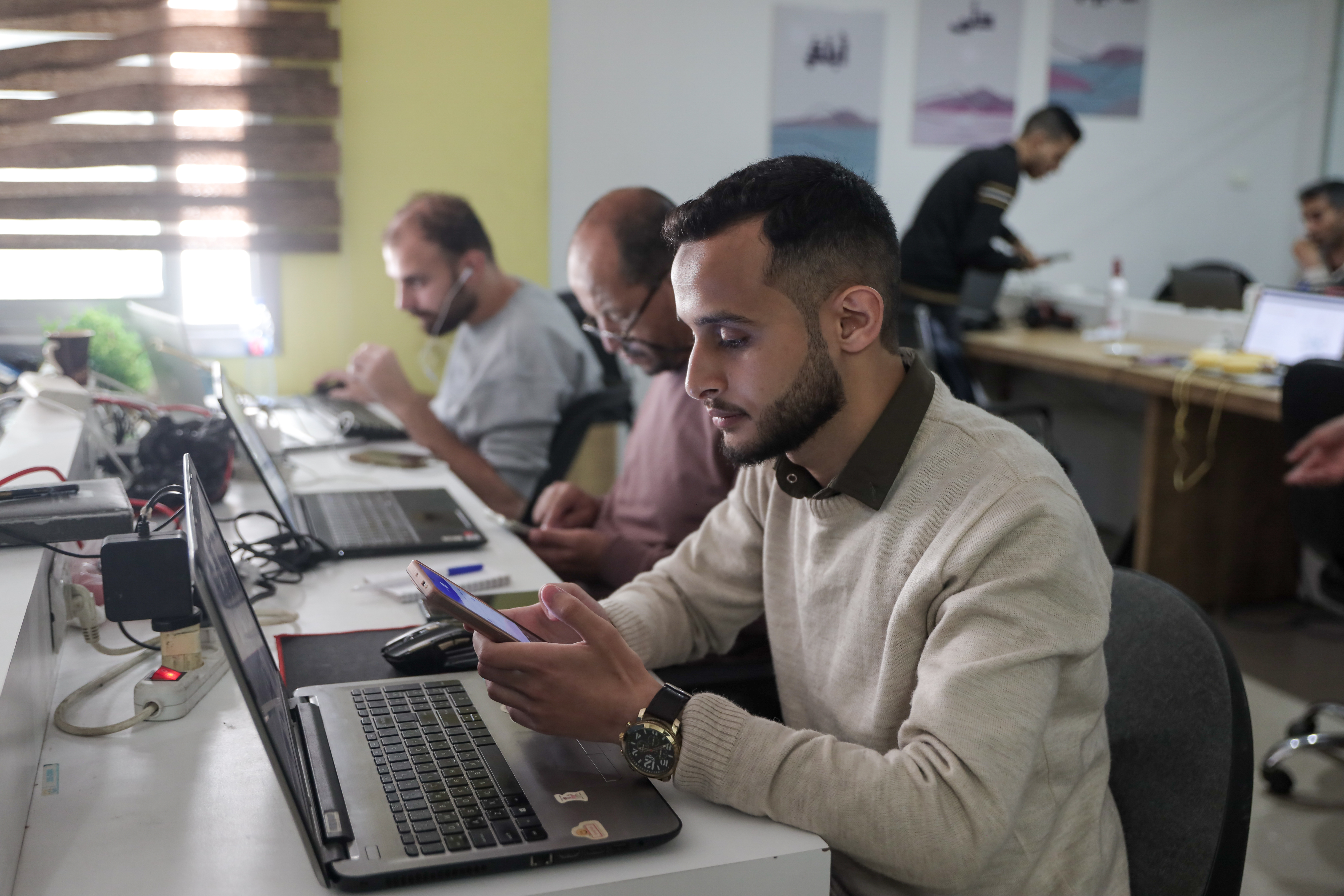 Man at desk working on a computer, others in the background