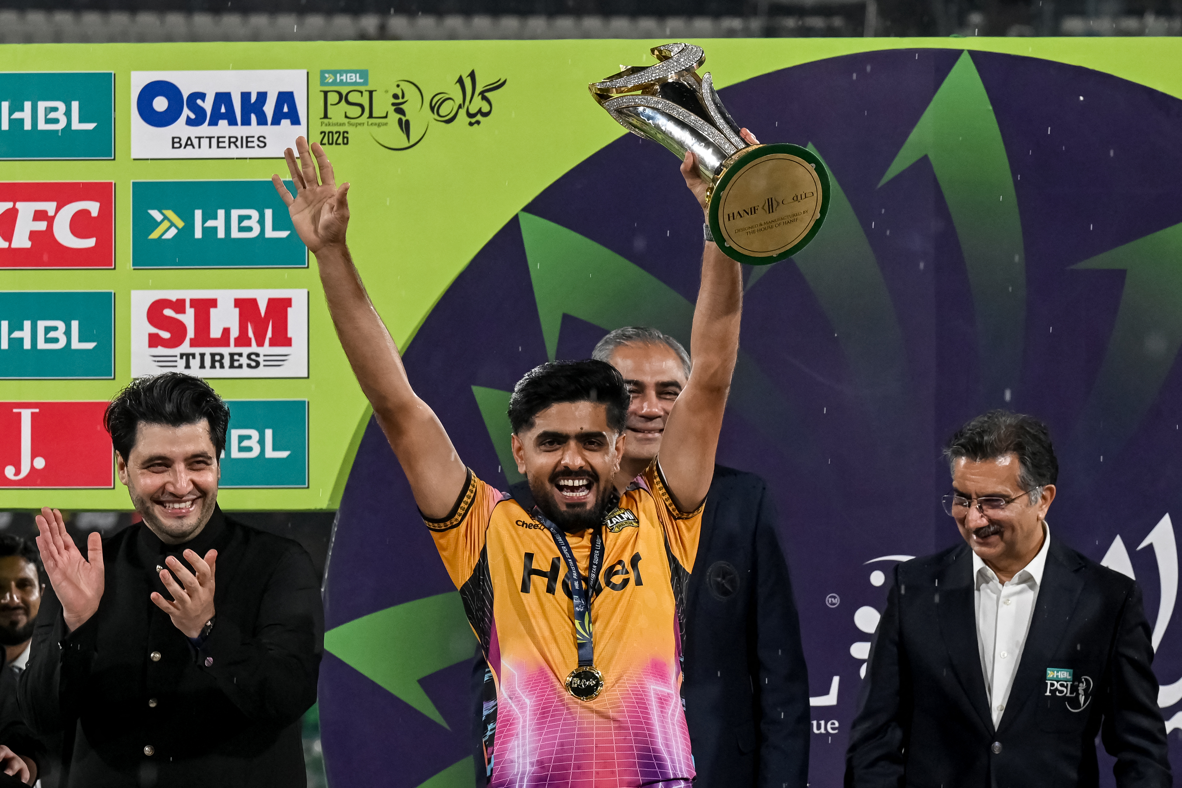 Pakistans cricket player and Peshawar Zalmi captain Babar Azam (C) celebrates after receiving the trophy from Pakistan Cricket Board (PCB) chairman Mohsin Naqvi (C, back) after winning the Pakistan Super League (PSL) Twenty20 final match against Hyderabad Kingsmen at the Gaddafi Stadium in Lahore on May 4, 2026. (Photo by Arif ALI / AFP)