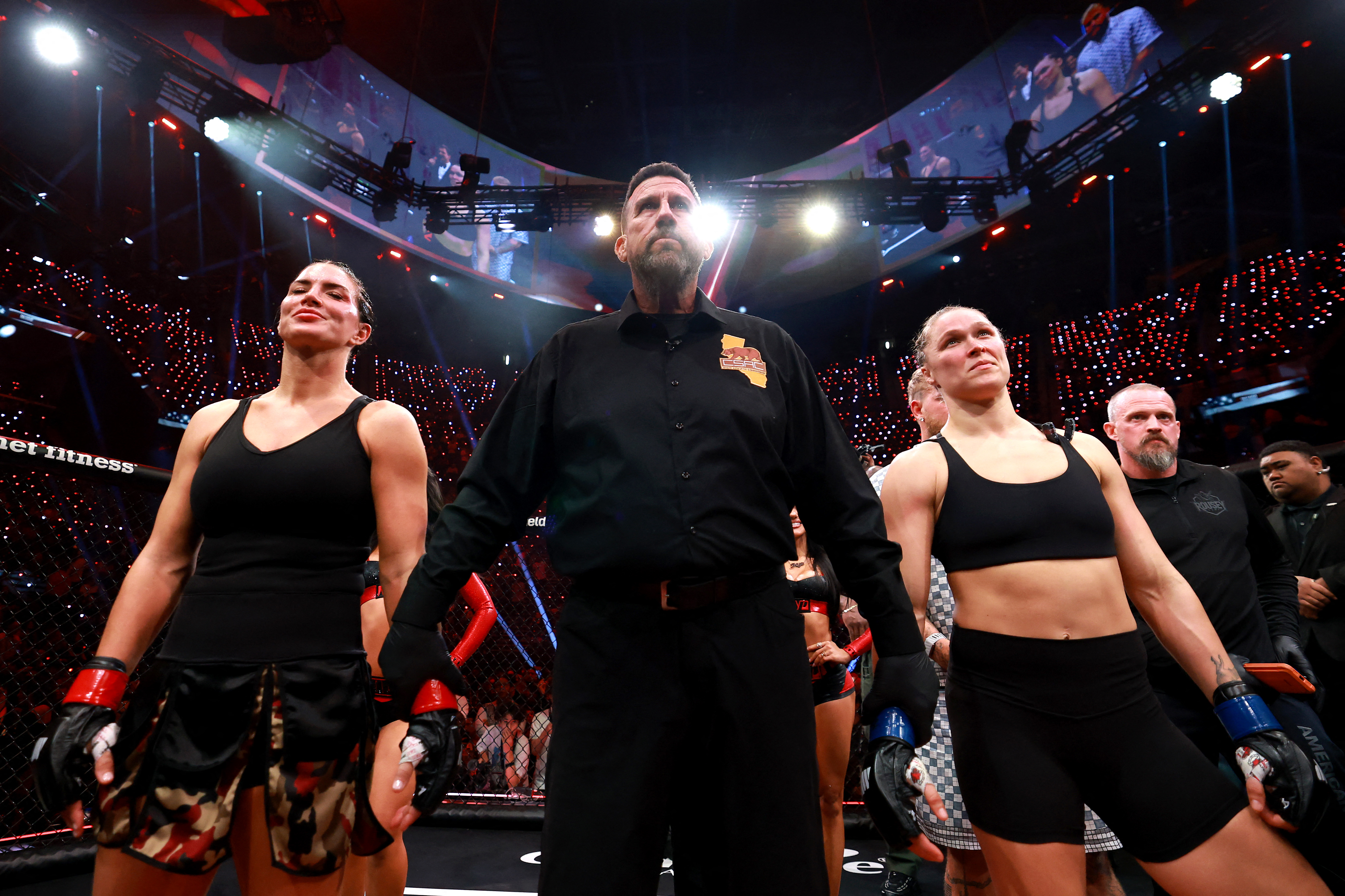 INGLEWOOD, CALIFORNIA - MAY 16: Gina Carano and Ronda Rousey stand with referee John McCarthy after their featherweight bout during the main card of Netflix's Ronda Rousey vs. Gina Carano at Intuit Dome on May 16, 2026 in Inglewood, California. Sarah Stier/Getty Images for Netflix/AFP (Photo by Sarah Stier / GETTY IMAGES NORTH AMERICA / Getty Images via AFP)