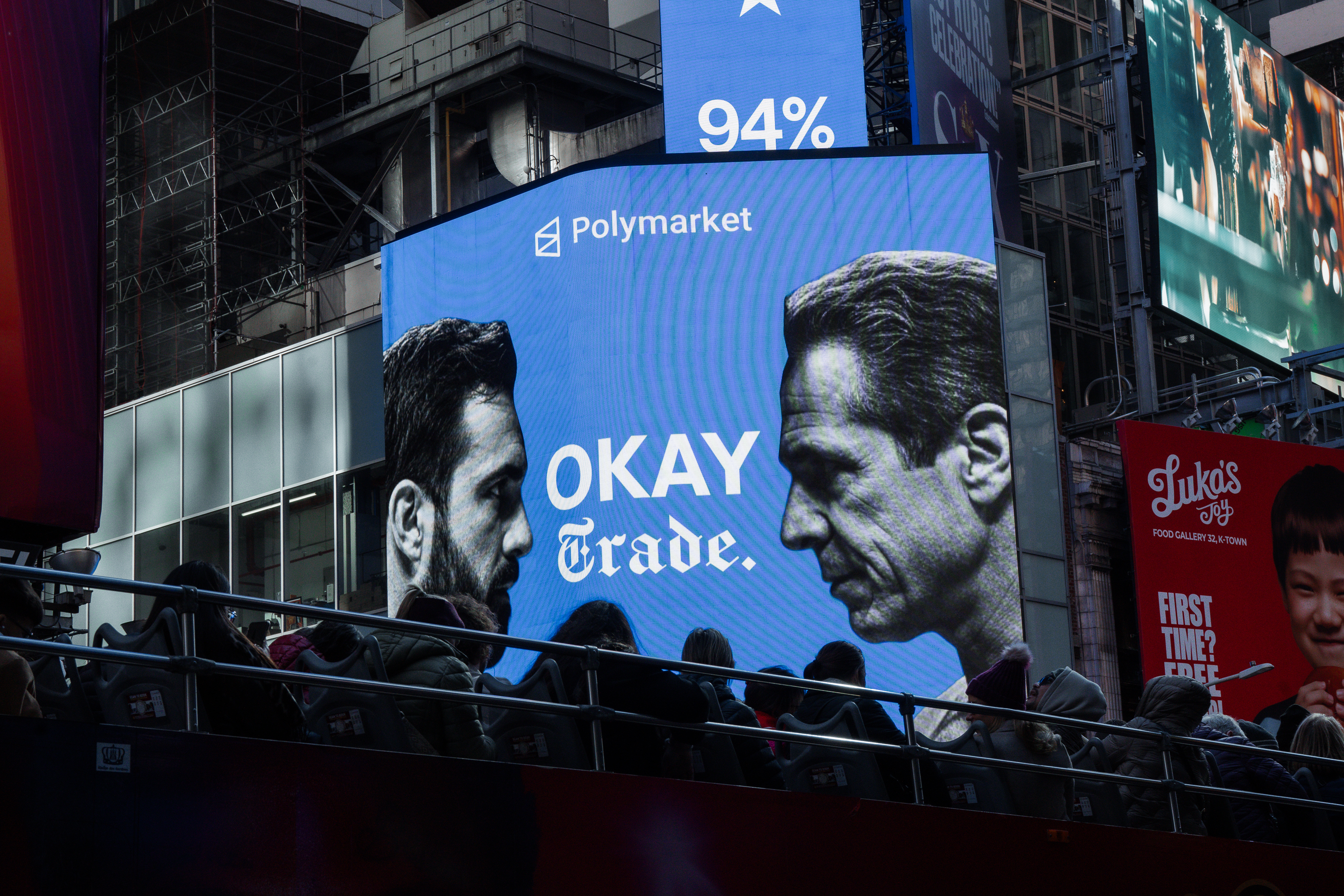 People walk past an electronic billboard showing candidates Zohran Mamdani and Andrew Cuomo