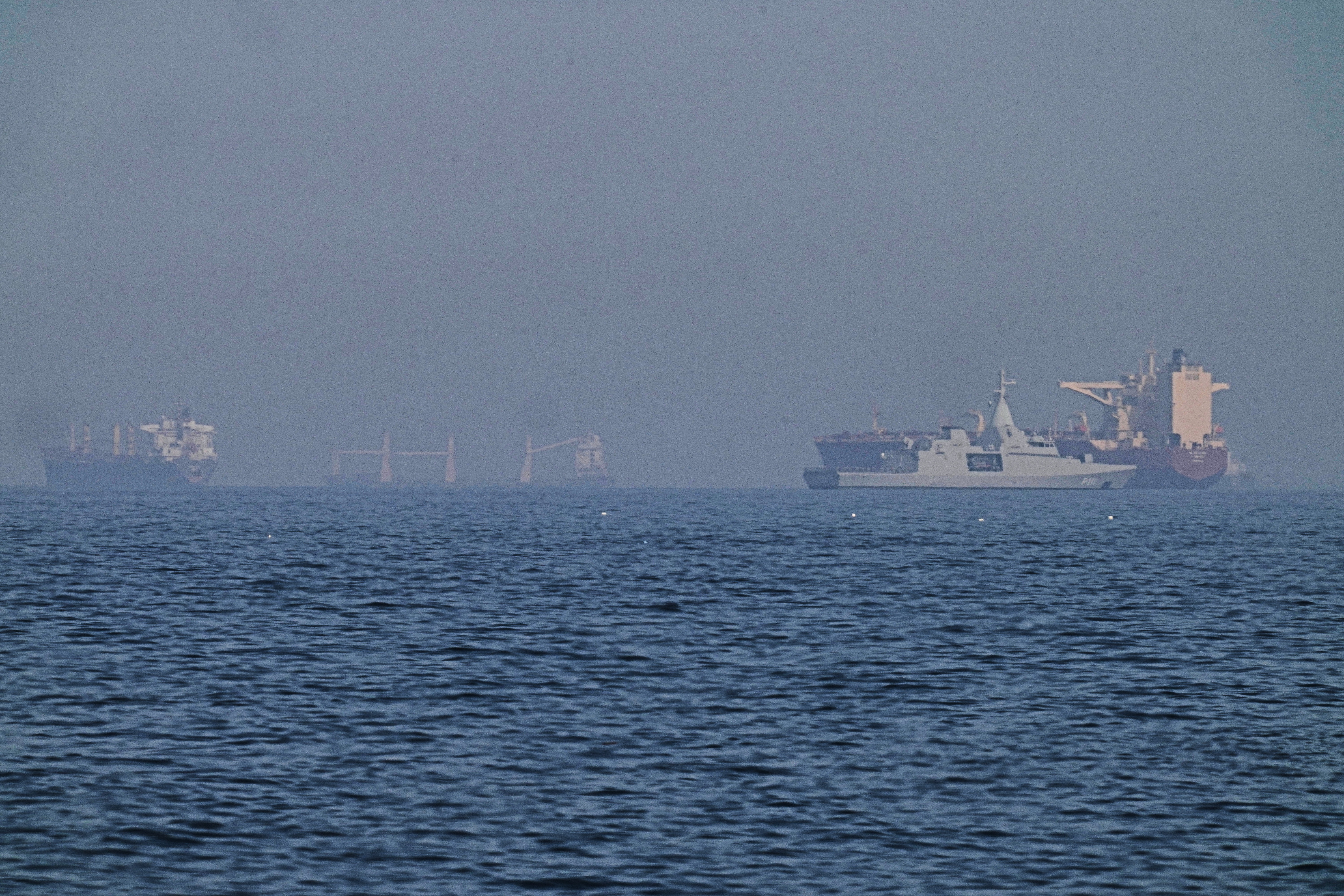 A patrol boat sails near a tanker.