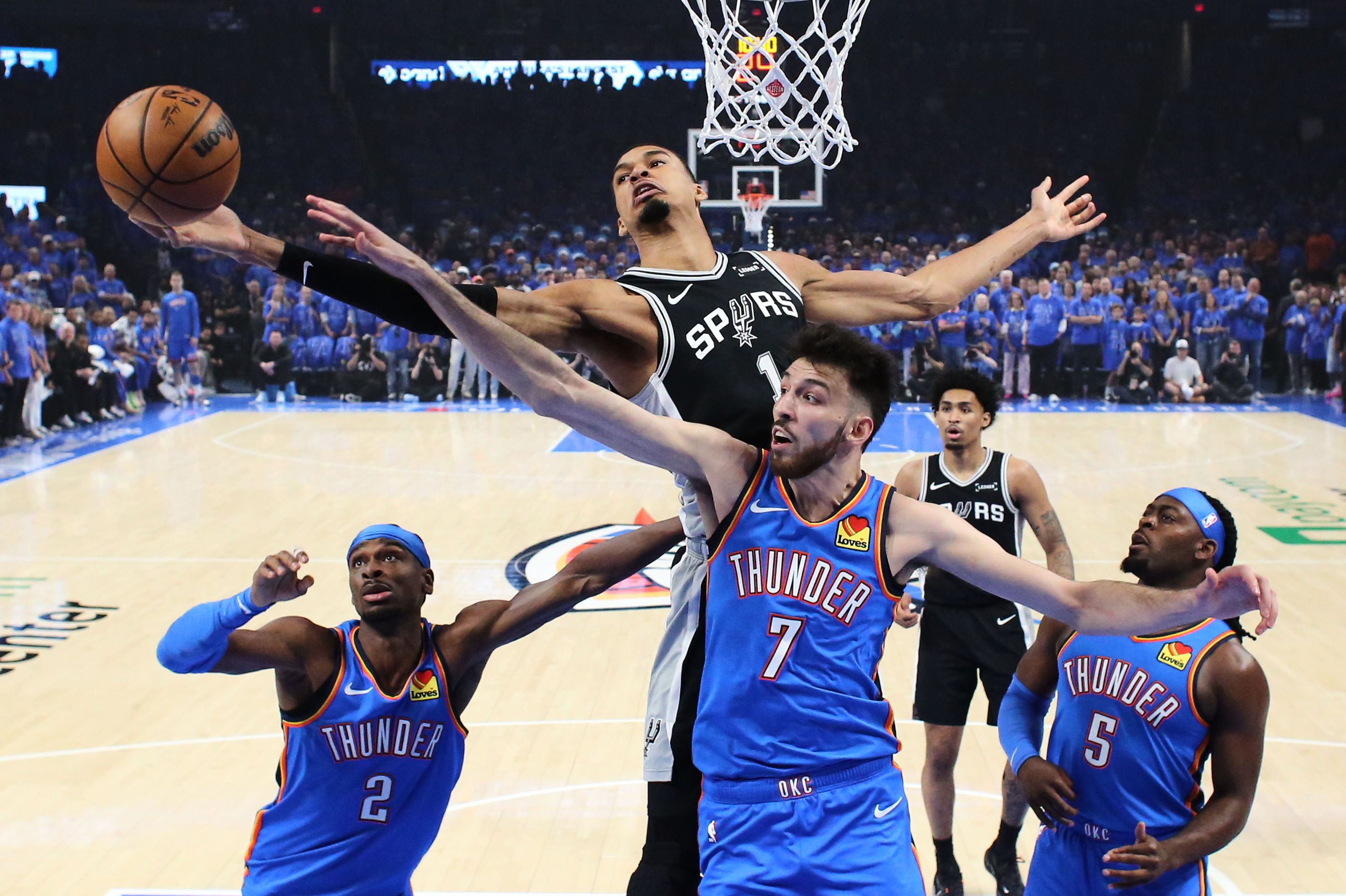 San Antonio Spurs forward Victor Wembanyama and Oklahoma City Thunder center Chet Holmgren reach for a rebound