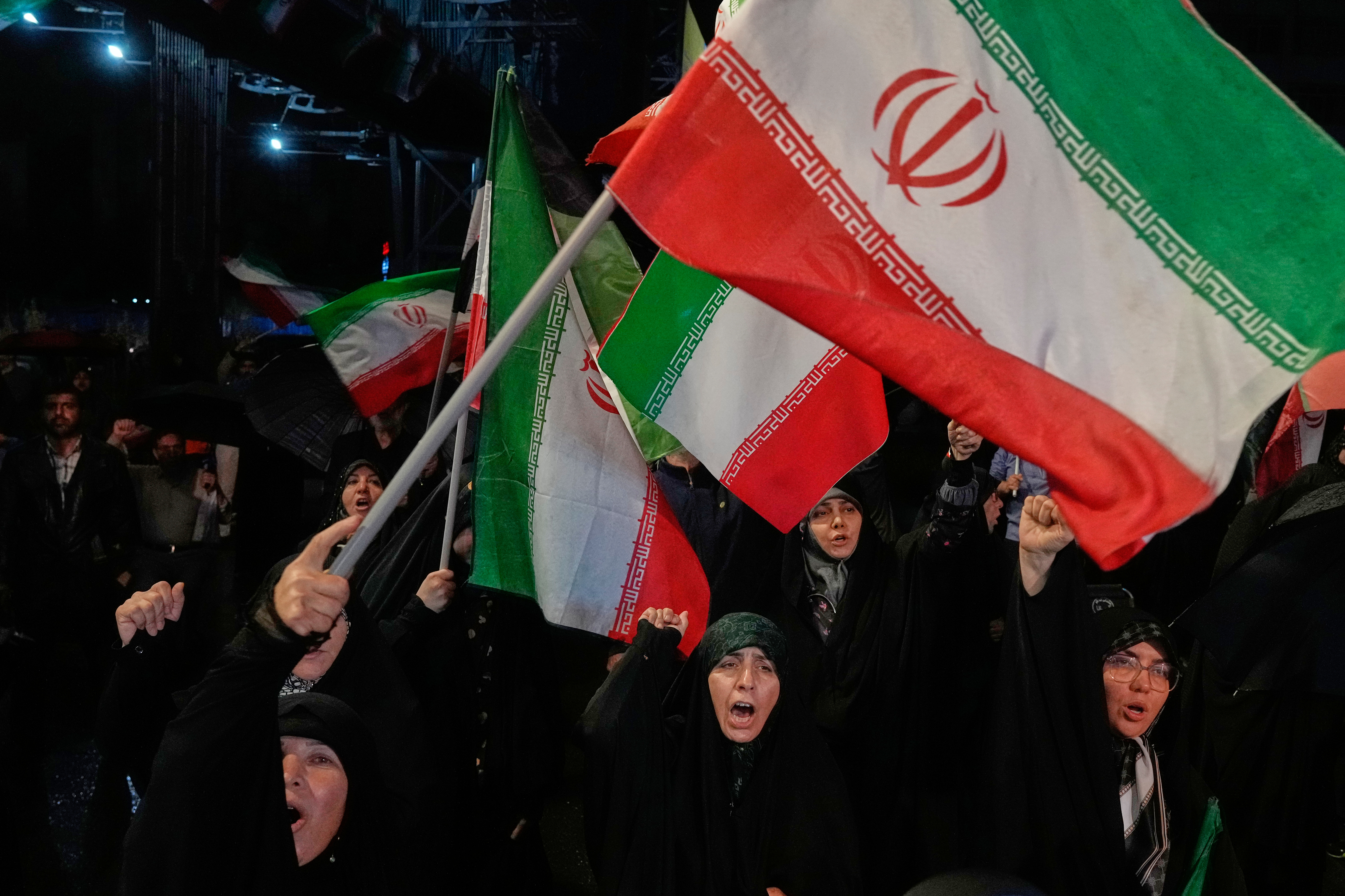Pro-government demonstrators chant slogans as they wave Iranian flags.