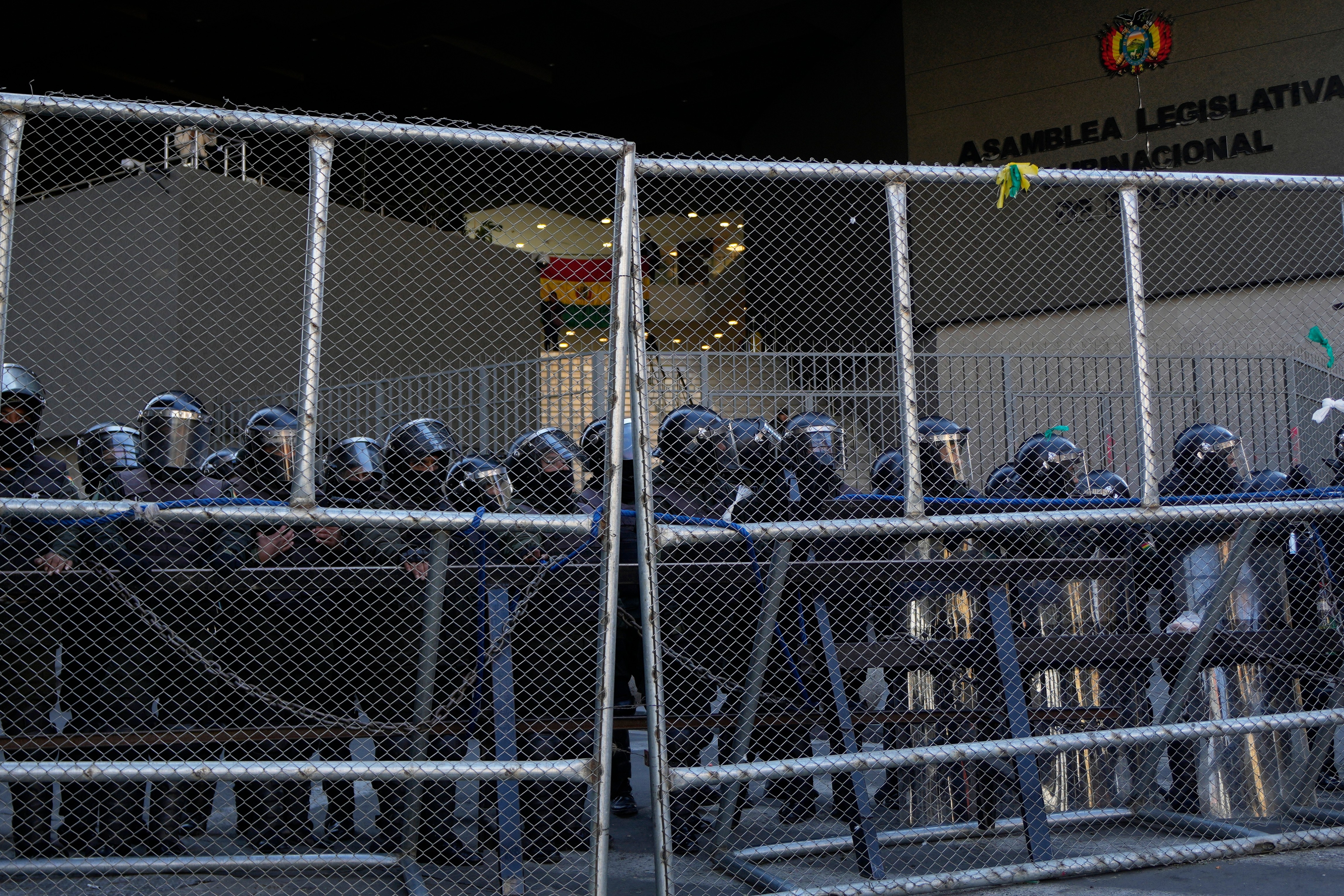 Police stand guard behind a fence during anti-government protests near the government palace in La Paz, Bolivia