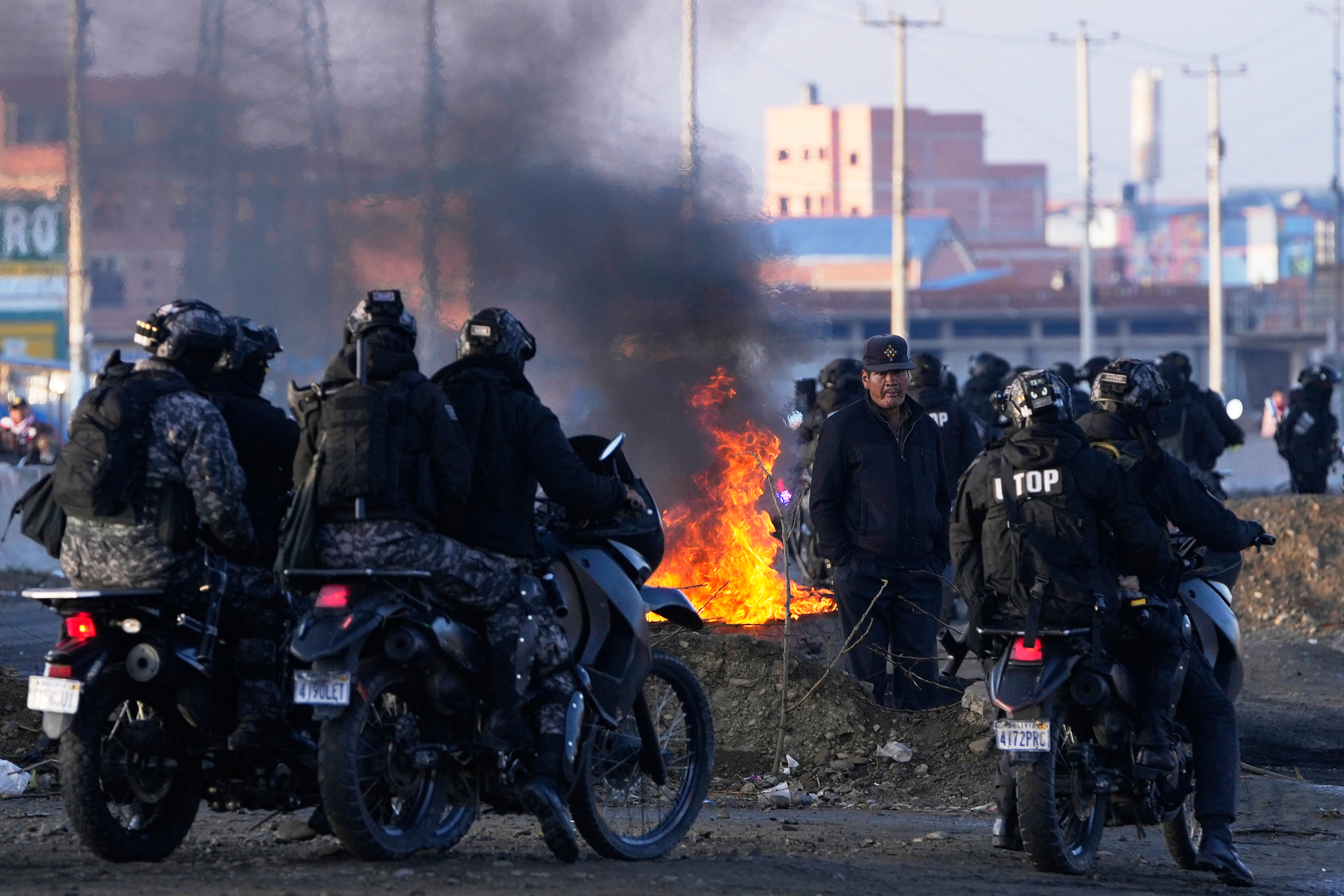 A resident walks past police near barricades set up by anti-government protesters on a highway in El Alto, Bolivia