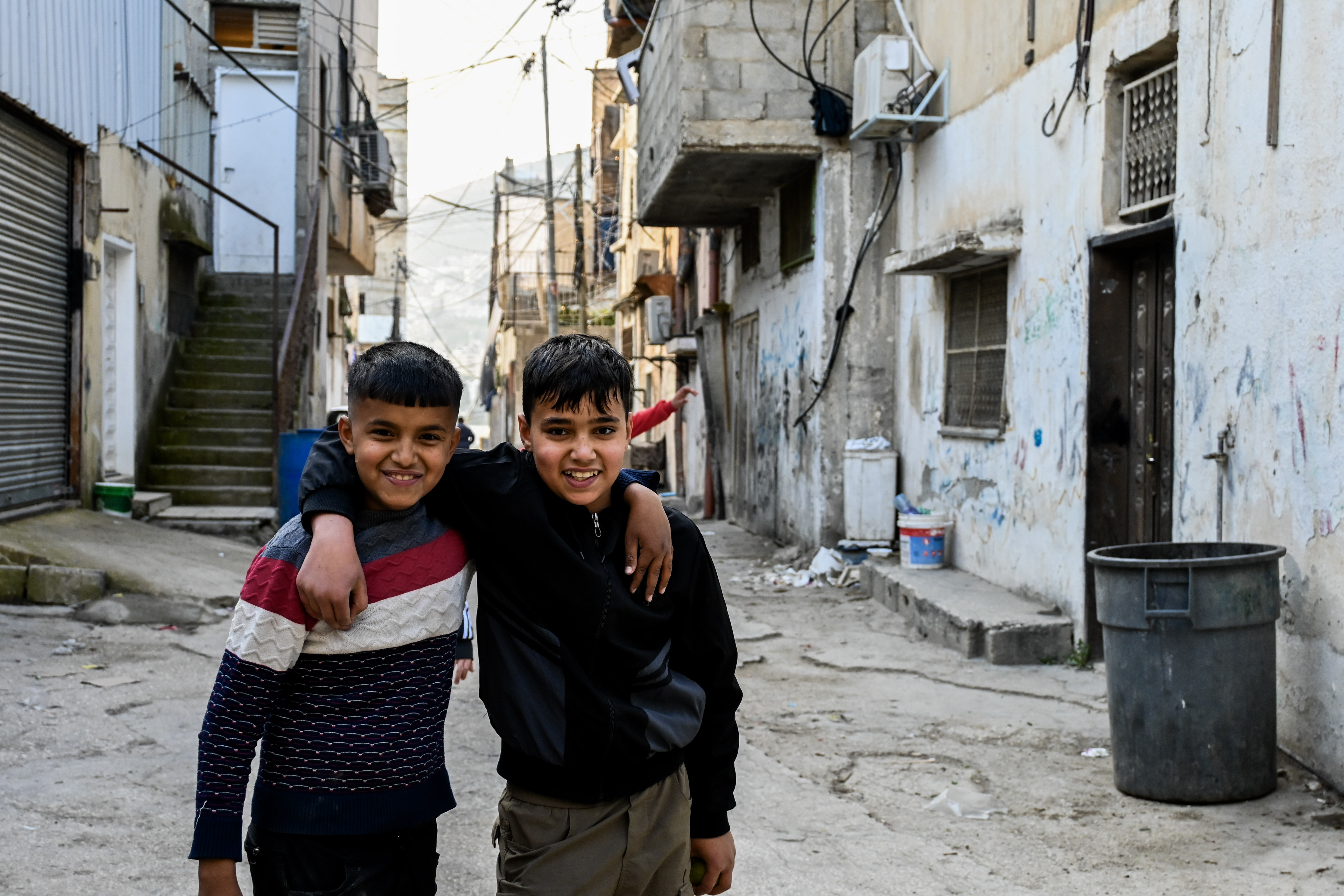 Two boys pose for a photo in a street in Askar refugee camp