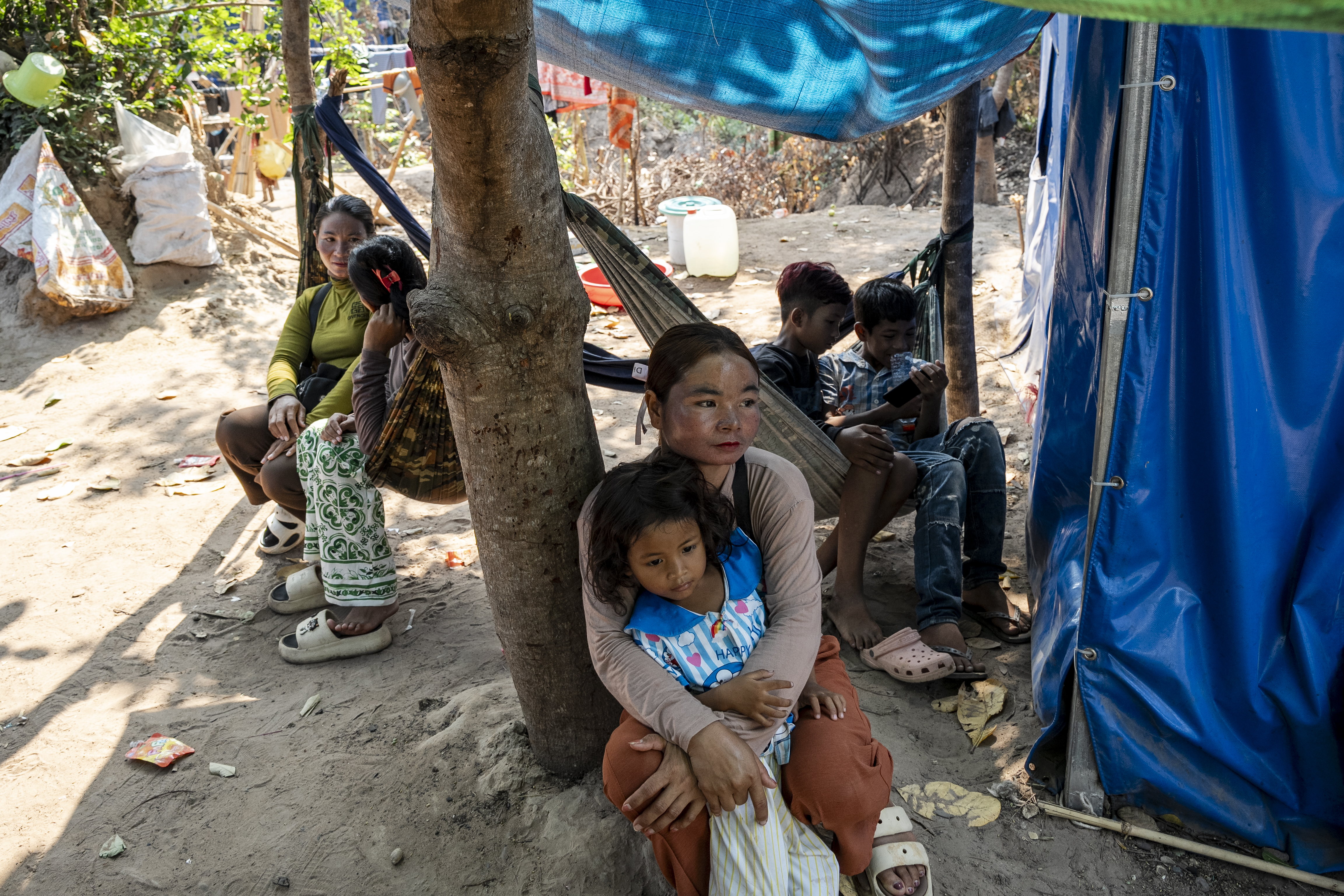 A woman holds her young daughter outside a tent.