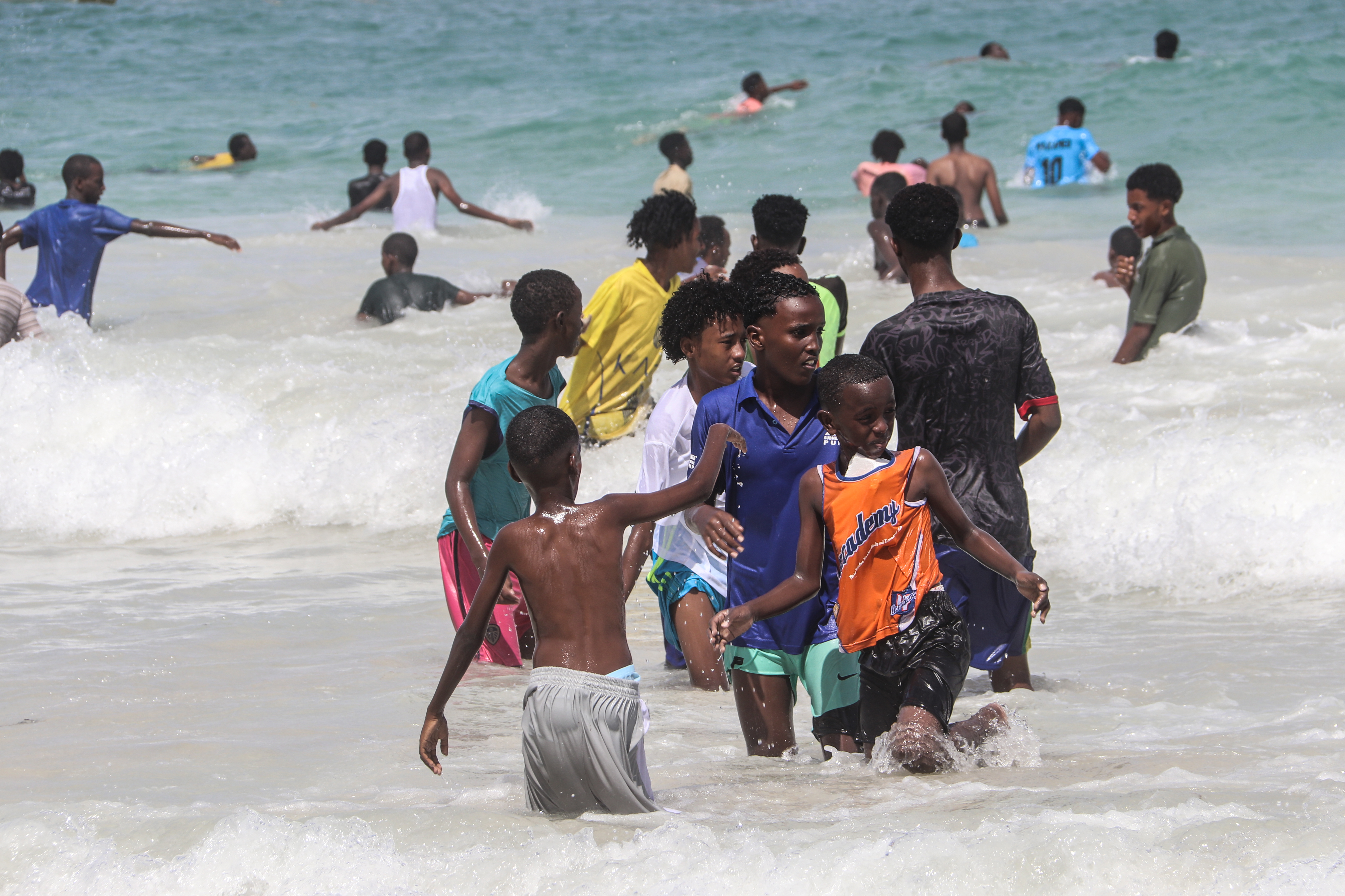 Young men play in the sea at Lido Beach in Mogadishu. [Faisal Ali/Al Jazeera]