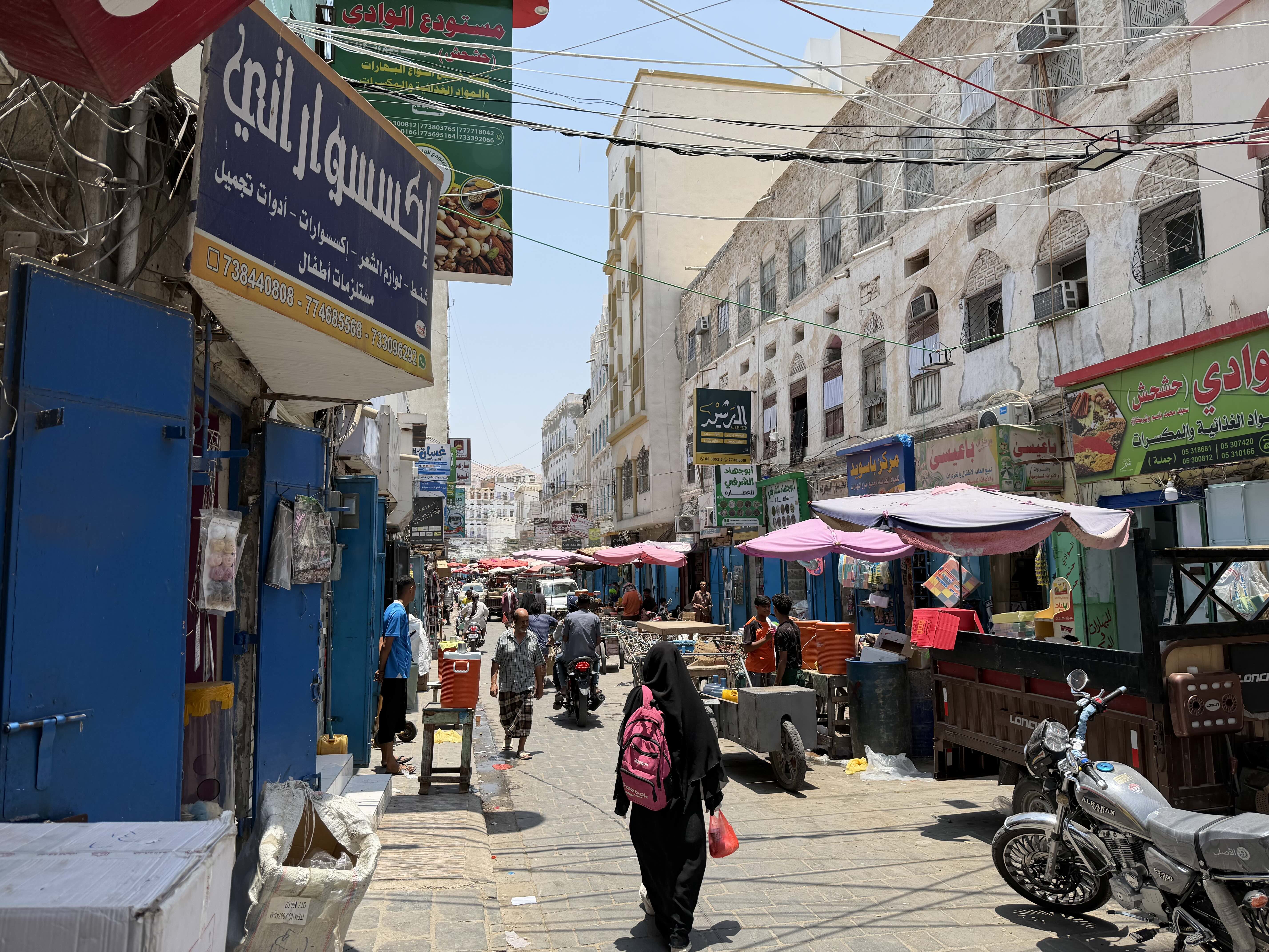 Shoppers move through a busy market in Mukalla on a hot afternoon, as residents brace for rising prices of essential goods following fuel hikes of more than 20 percent approved by the Yemeni government