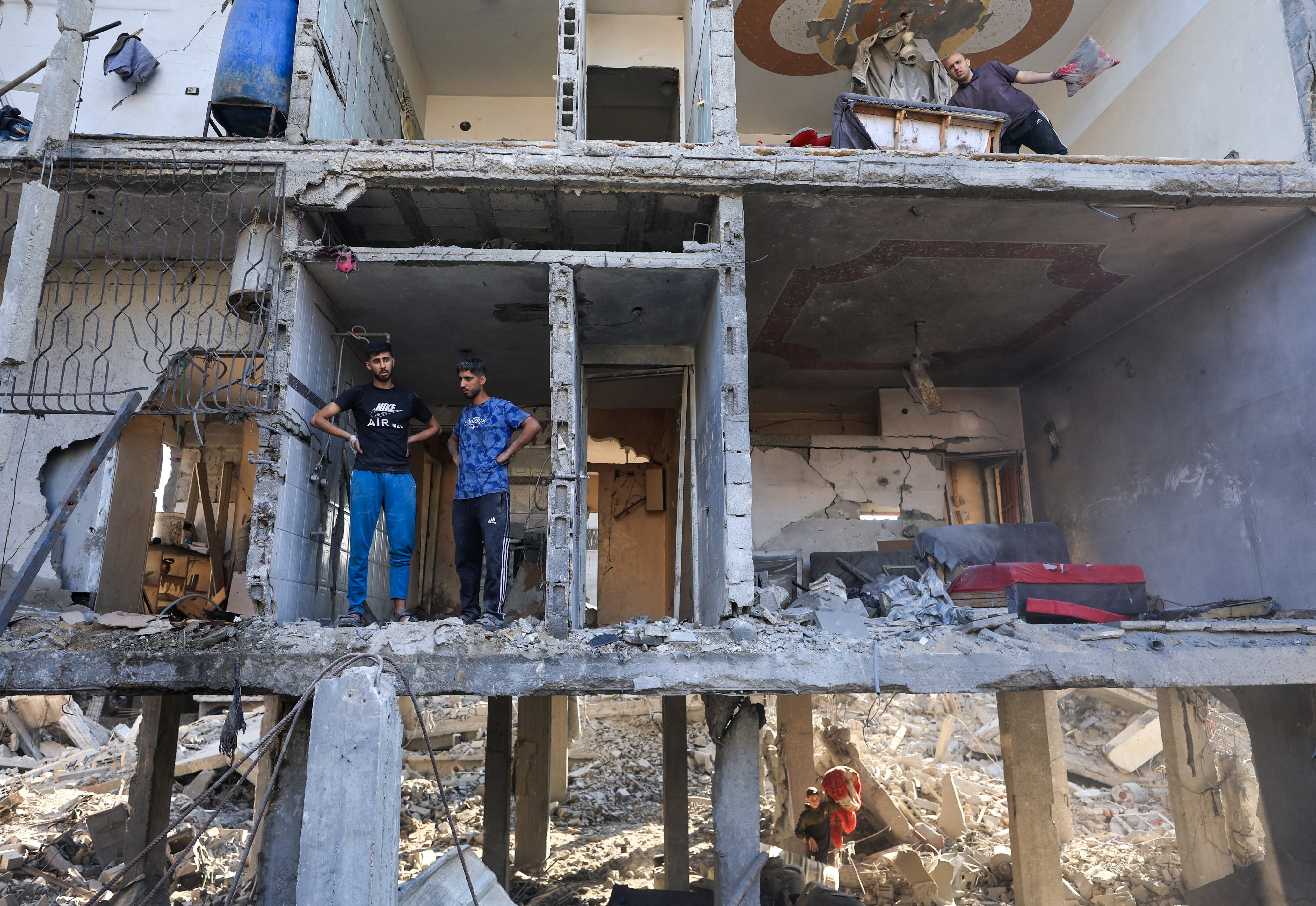 Palestinians inspect the site of an Israeli strike on a house
