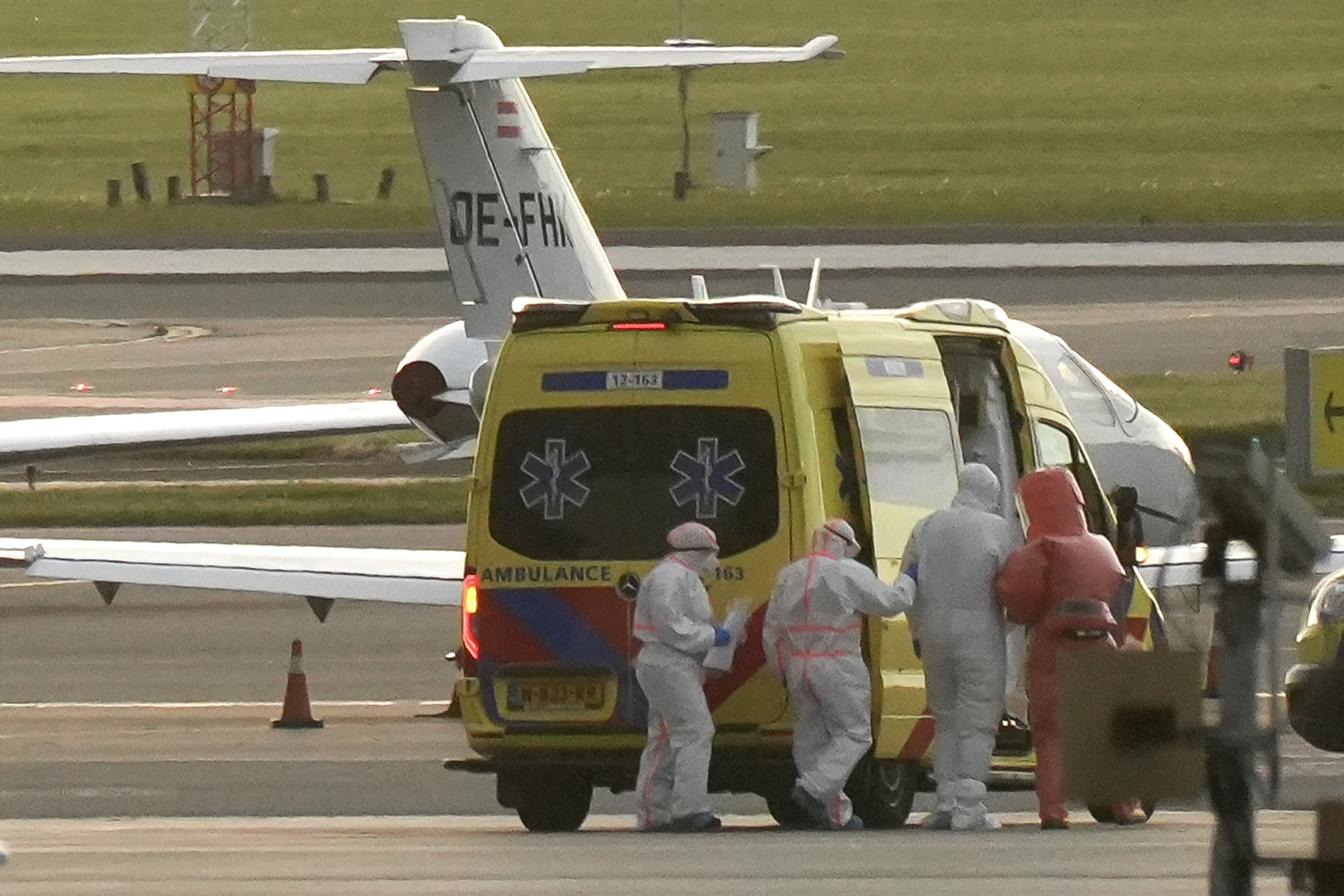 TOPSHOT - A person in a hazmat suit (2R) is escorted to a ambulance from a medical aircraft allegedly carrying some of the passengers from the cruise ship MV Hondius believed to be infected with hantavirus, at Schiphol airport near Amsterdam on May 6, 2026.