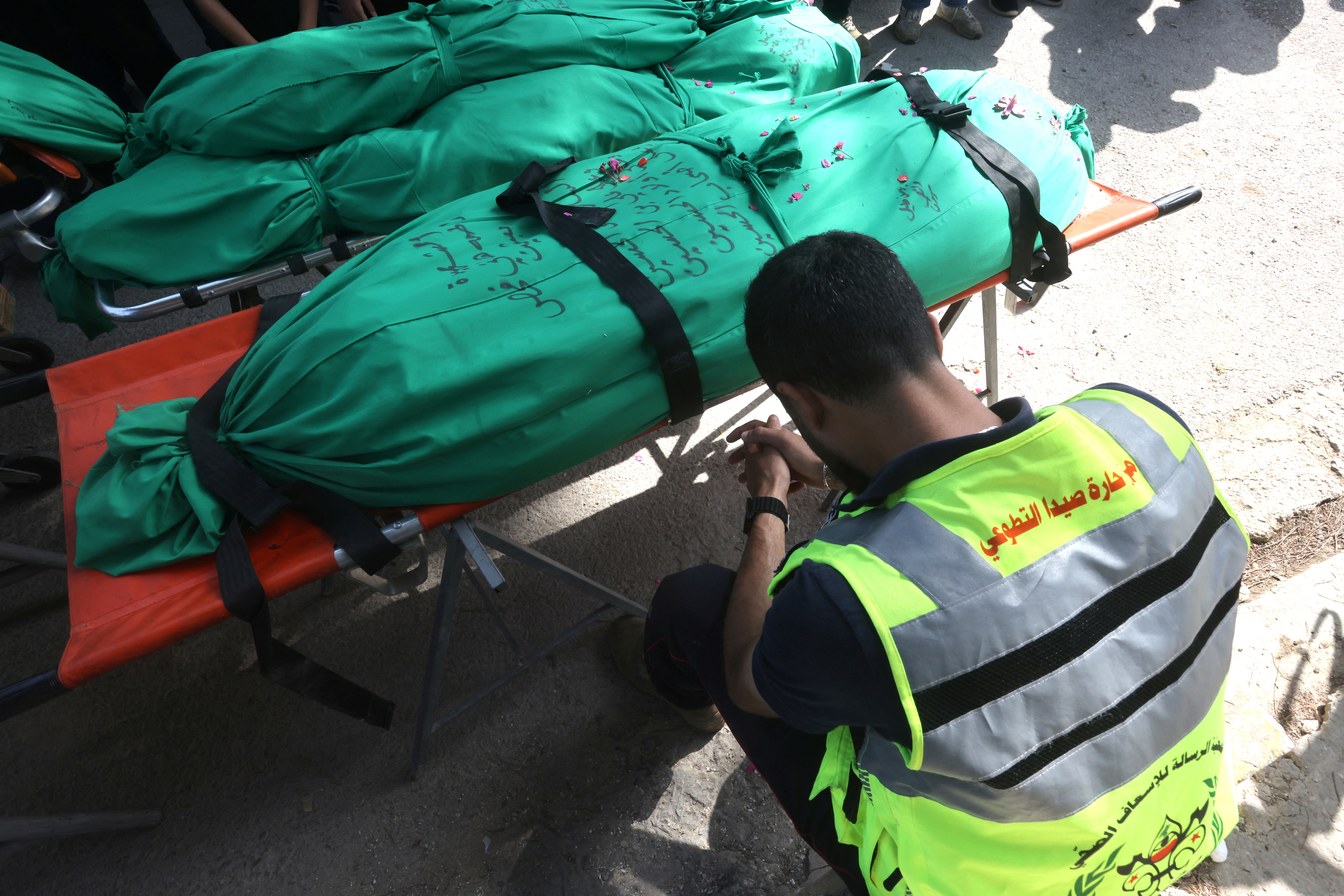 A Lebanese civil defence volunteer sits next to the bodies of the nine people killed the day before in an Israeli airstrike on the southern Lebanese village of Jibshit, during the preparations for their funeral in the city of Sidon on May 10, 2026.