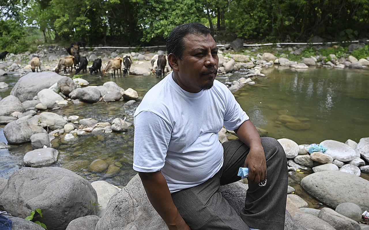 (FILES) Honduran environmentalist Juan Lopez sits on a rock as he watches the Guapinol river on the outskirts of Tocoa, Colon department, Honduras, on September 28, 2021.