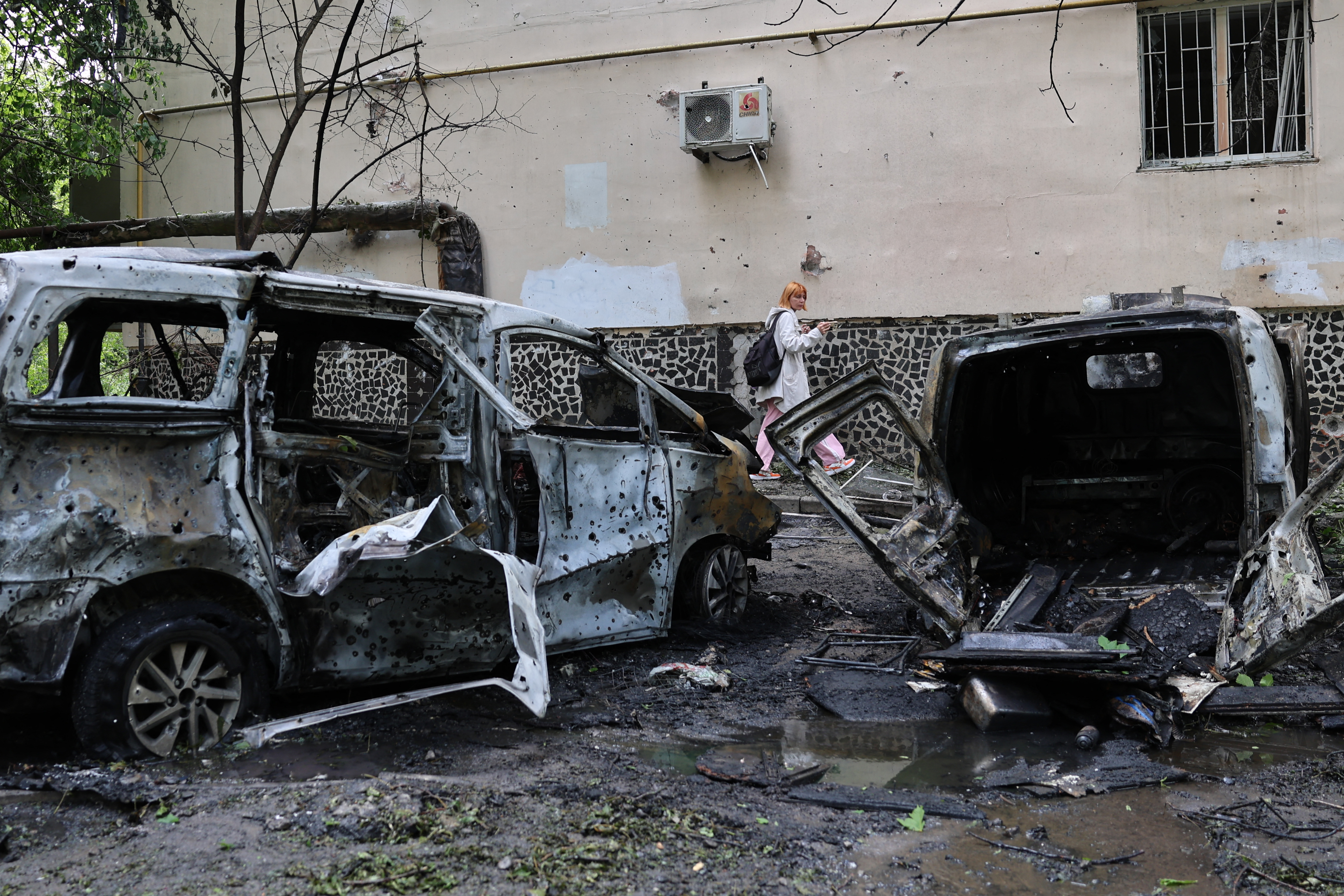 A woman walks past destroyed cars in the courtyard of a damaged residential building following an air attack in Odesa on May 13, 2026, amid the Russian invasion in Ukraine.