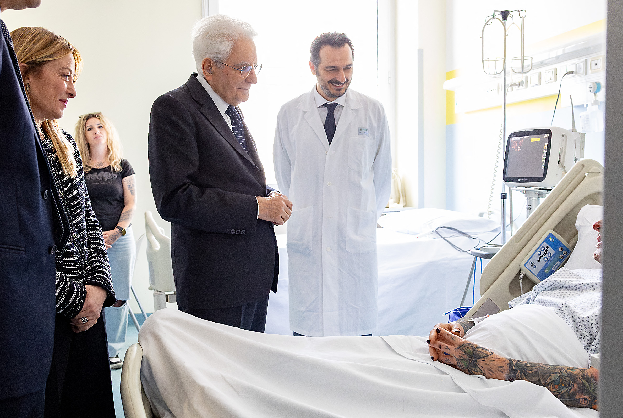This handout picture released by the Quirinale Press office shows the President of Italy Sergio Mattarella, along with Italy's Prime Minister, Giorgia Meloni (L), during a visit to the victims of the attempted massacre of 16 May in Modena, in the Hospital of Modena on May 17, 2026.