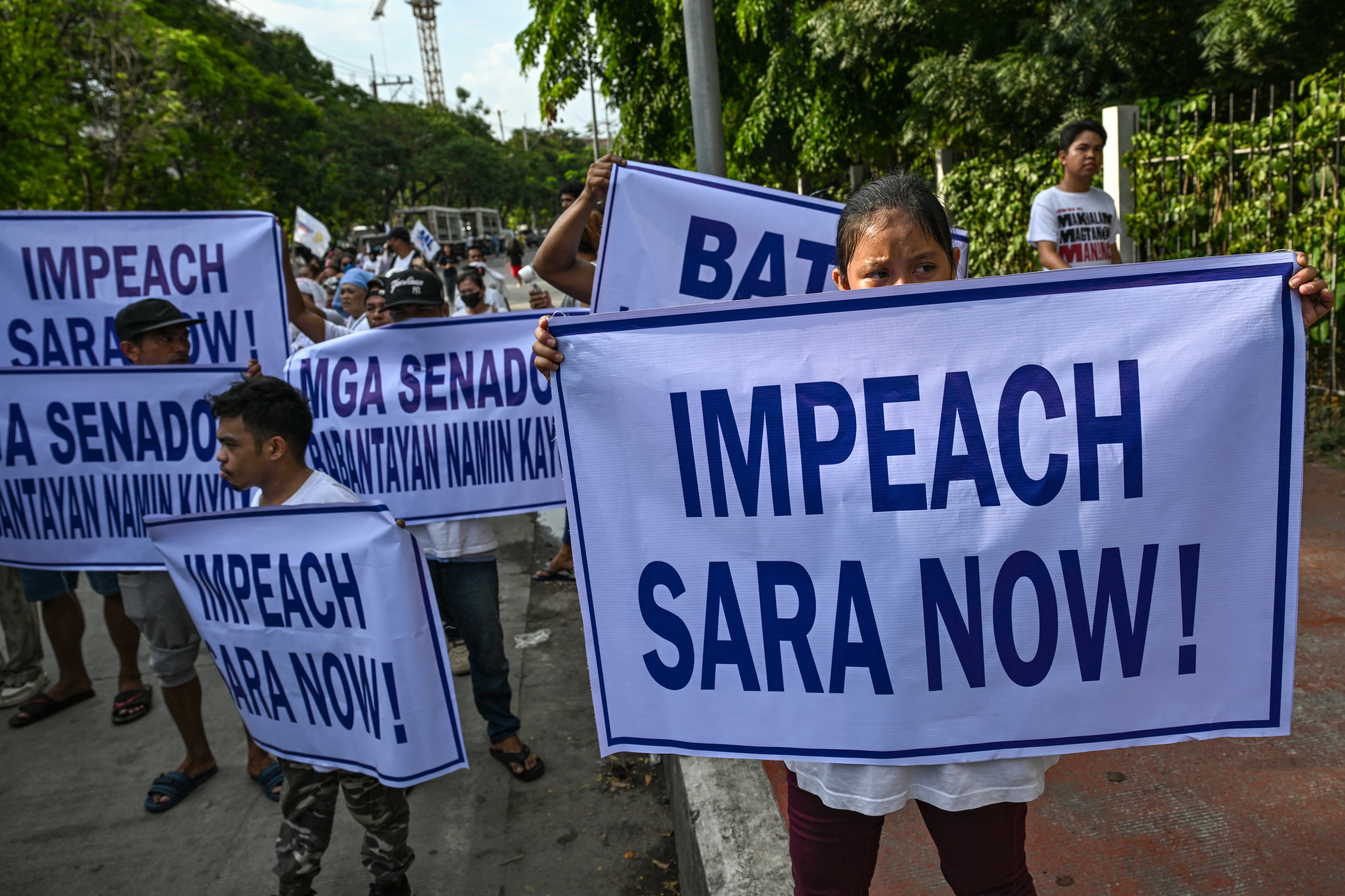 Protesters hold signs during a demonstration to call for the start of the impeachment trial against Philippine Vice-President Sara Duterte and the arrest of Philippine Senator Ronald "Bato" Dela Rosa outside the Senate of the Philippines in Pasay, Metro Manila on May 18, 2026.