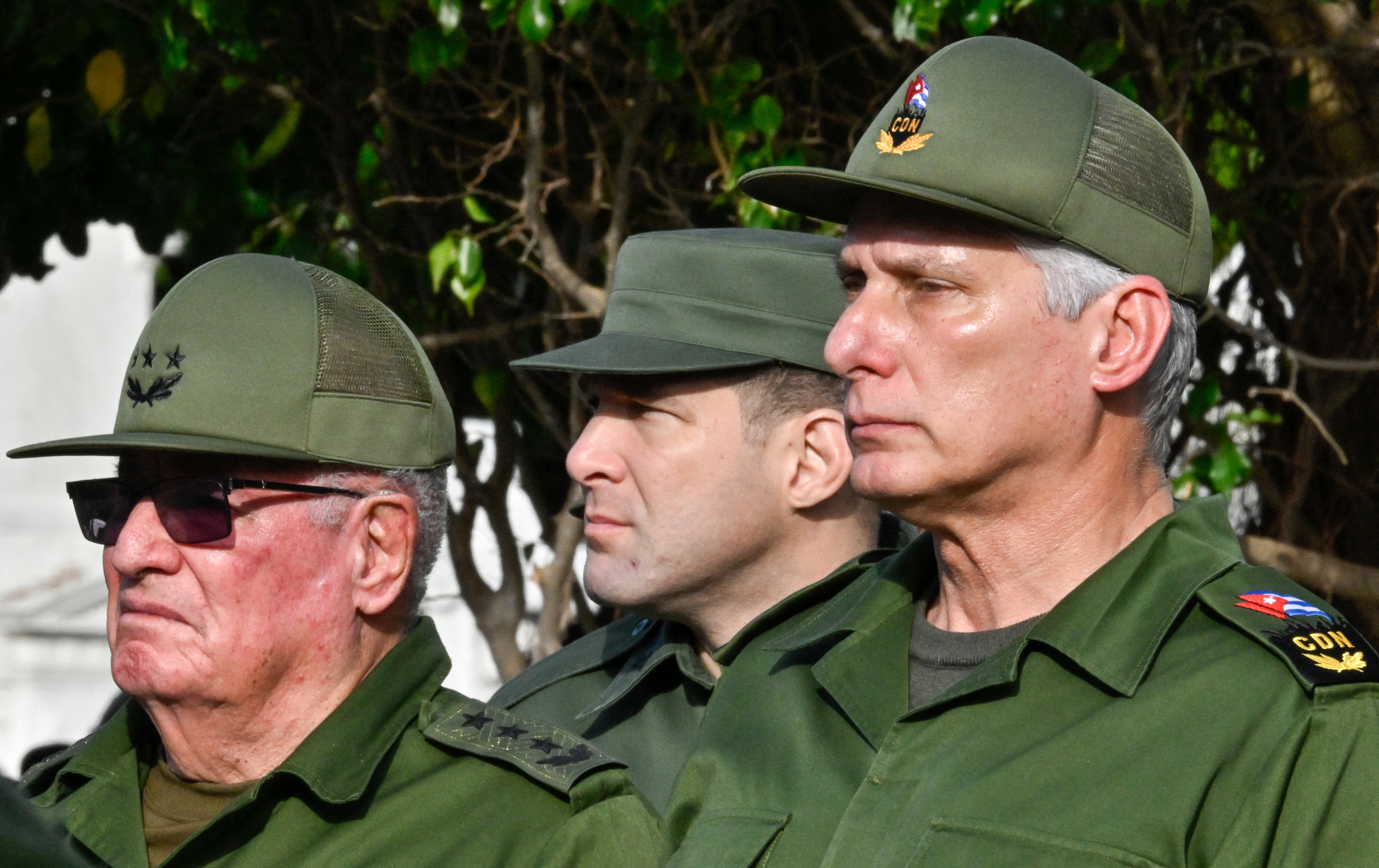 Cuba's President Miguel Diaz-Canel (R), Colonel Raul Guillermo Rodriguez Castro (C), grandson of former President Raul Castro, and Armed Forces Minister General Alvaro Lopez Miera attend the funeral of the 32 Cuban soldiers killed during the US incursion in Venezuela at Colon cemetery in Havana on January 16, 2026.