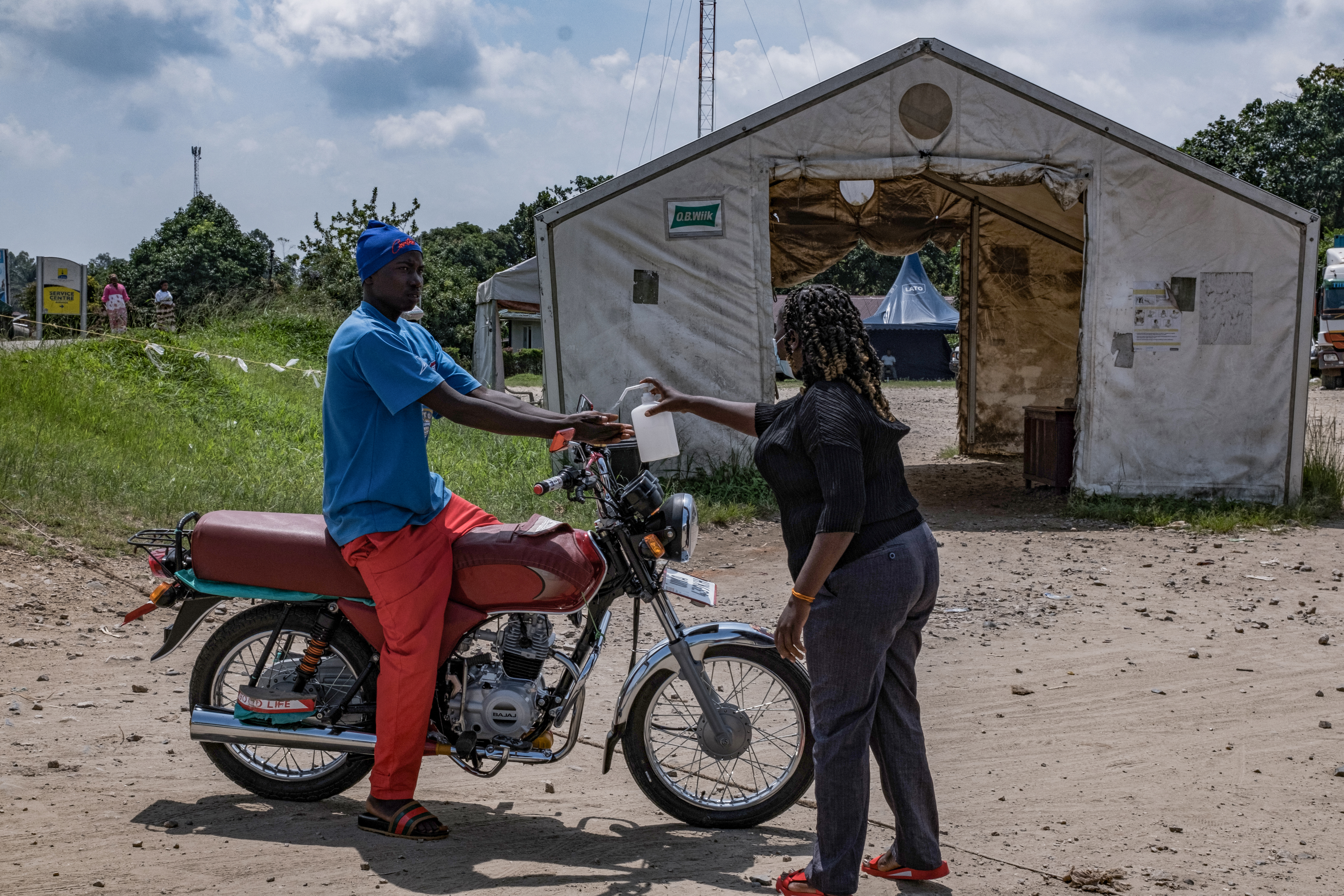 A port health officer sanitizes the hands of a motorbike rider at the Busunga border crossing between Uganda and the Democratic Republic of Congo in Bundibugyo, on May 18, 2026.