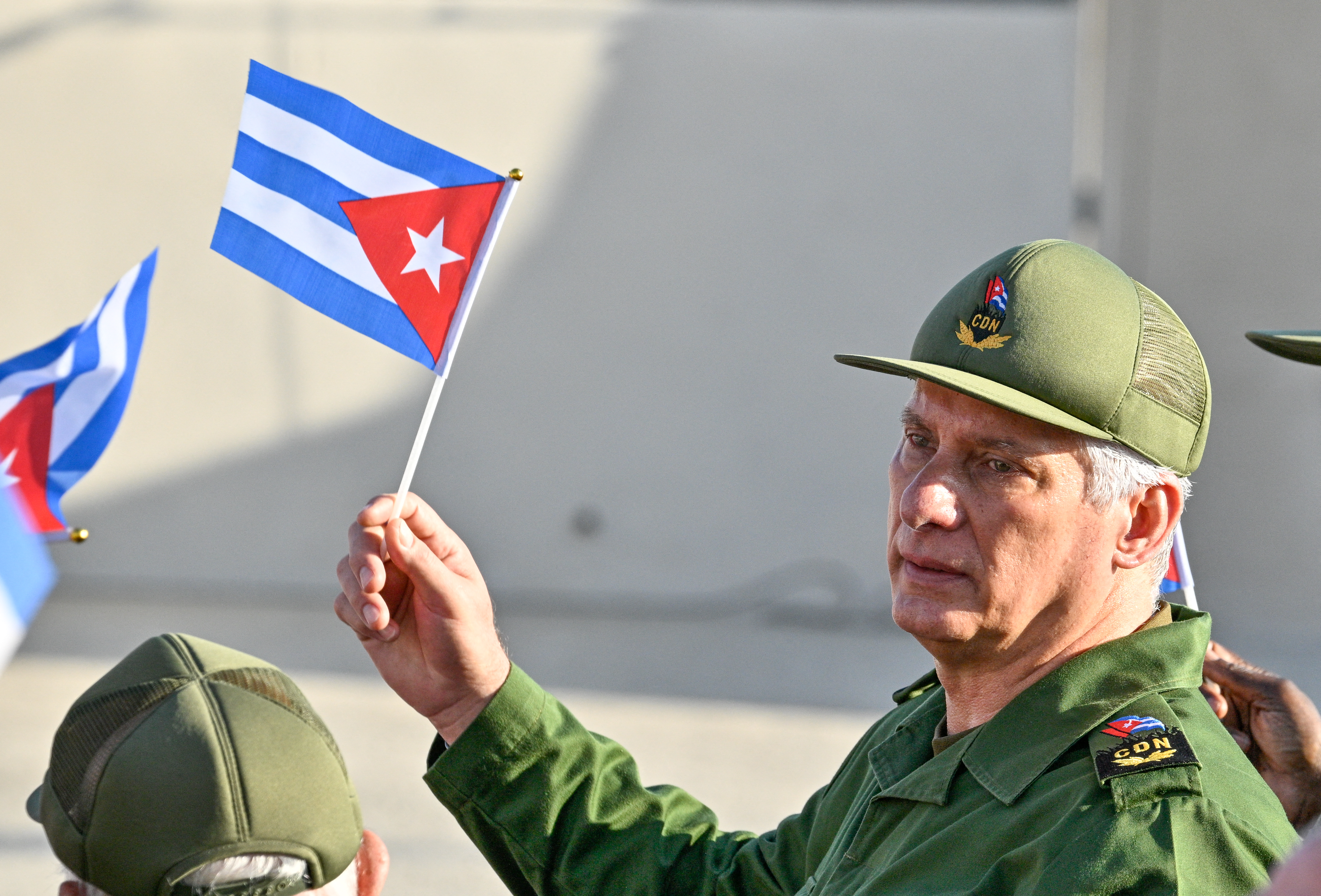 Cuba's President Miguel Diaz-Canel holds a Cuban flag during a rally in support of former Cuban president Raul Castro, 94, who has been indicted by a US court, outside the US Embassy in Havana on May 22, 2026. (Photo by ADALBERTO ROQUE / AFP)
