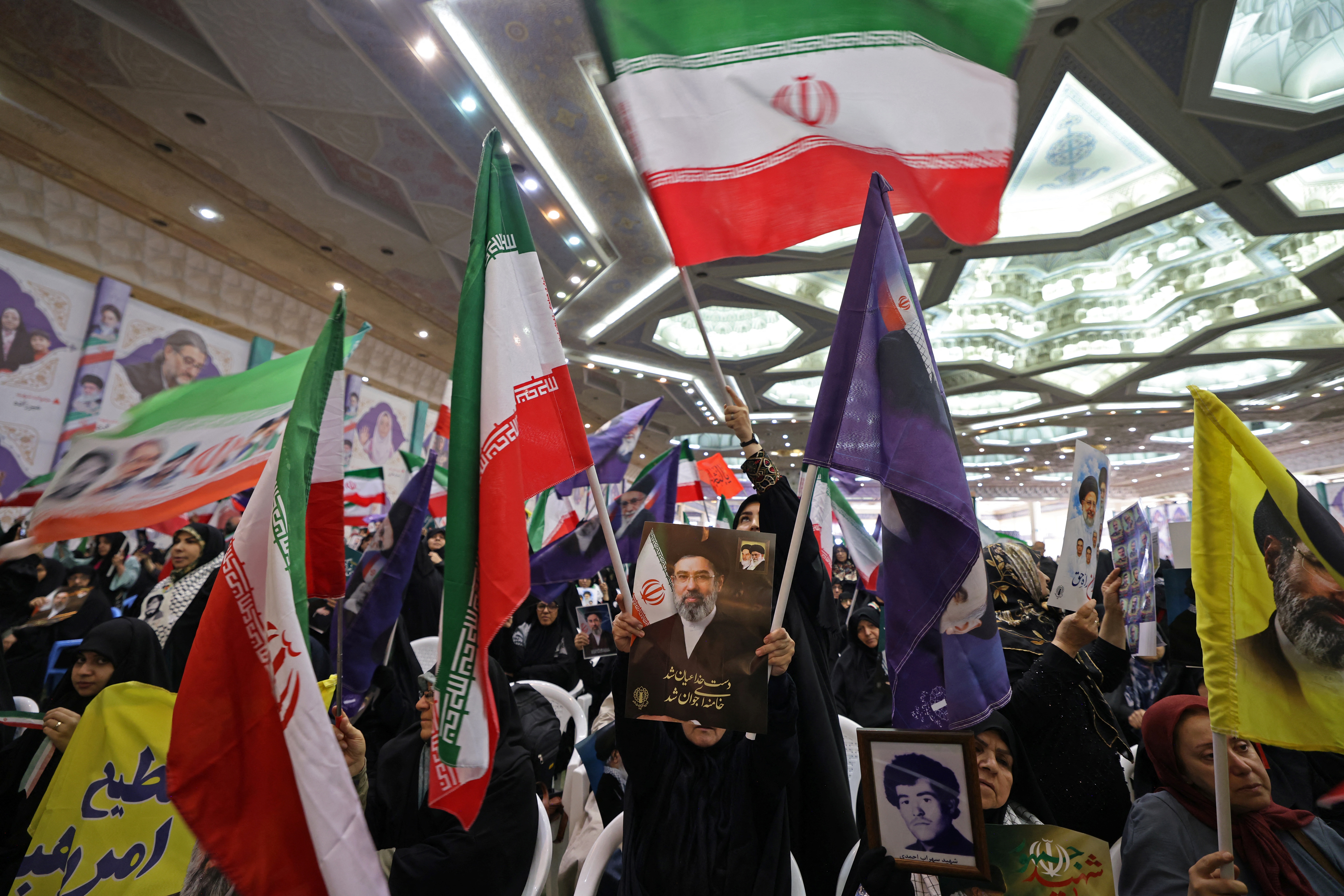 Iranians wave their national flag as they gather at Imam Khomeini Mosque to commemorate those killed in wars, in Tehran