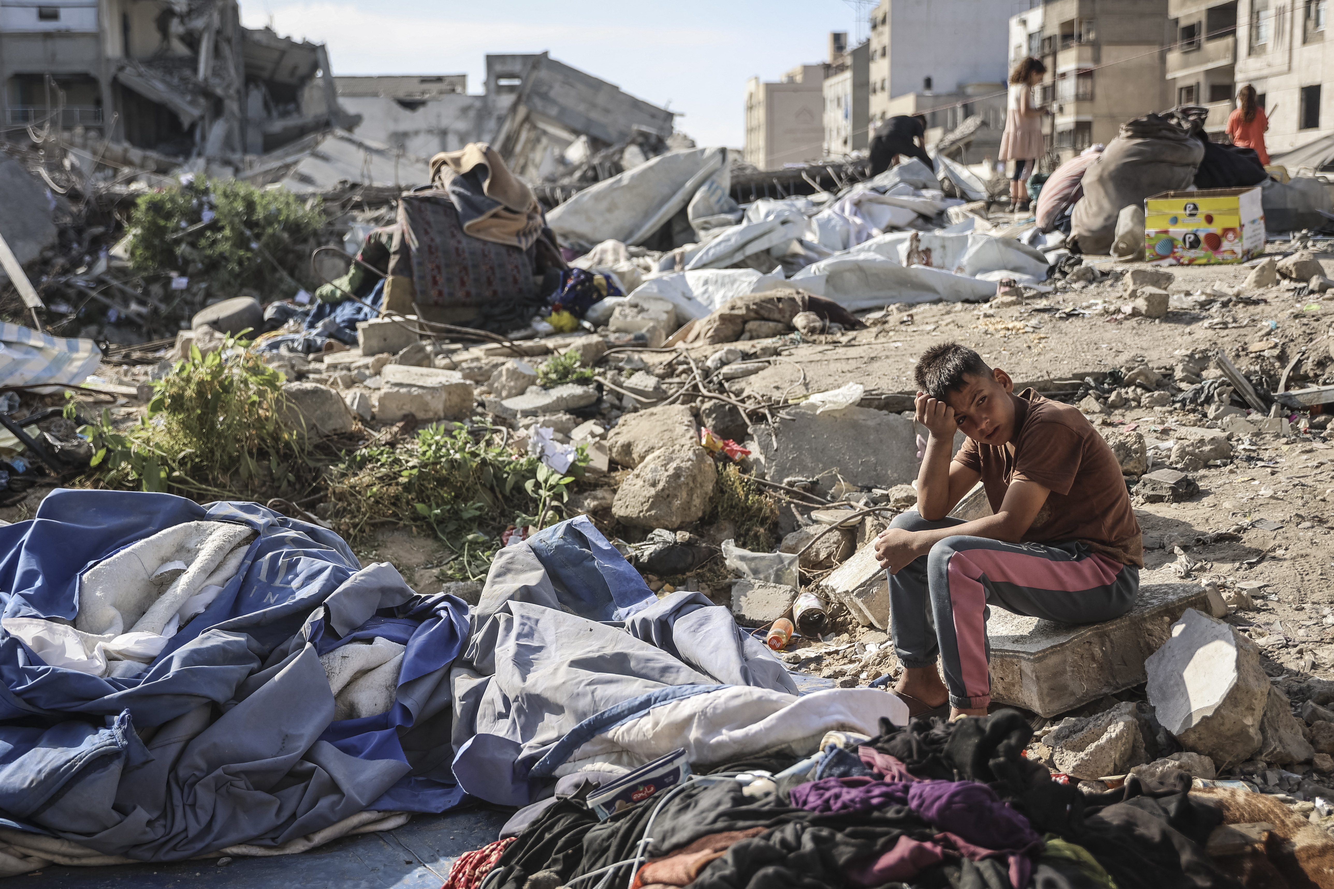 A Palestinian boy sits at the site of an overnight Israeli military strike on structures and tents housing displaced families in Gaza City