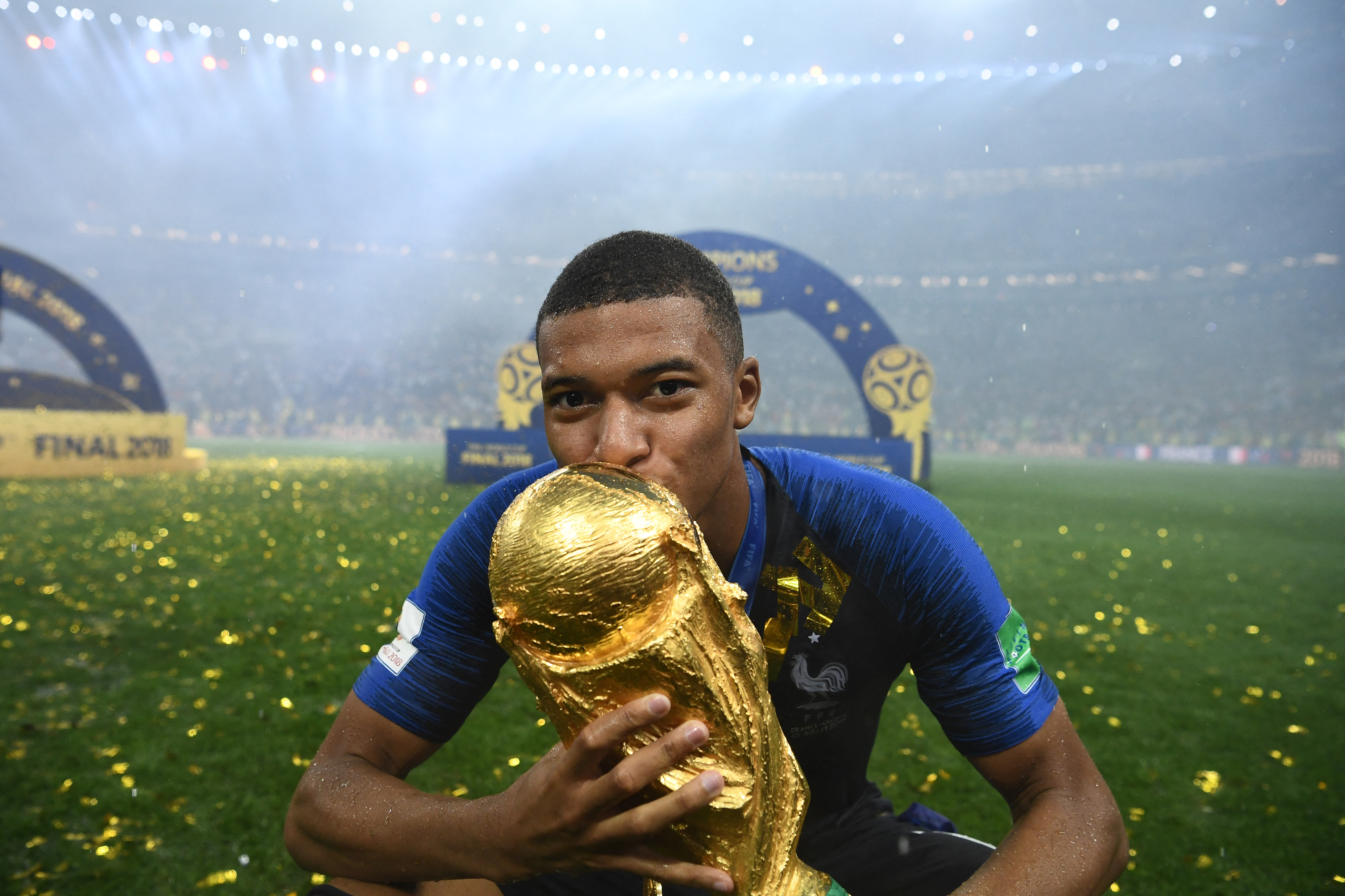 France's forward Kylian Mbappe kisses the World Cup trophy.