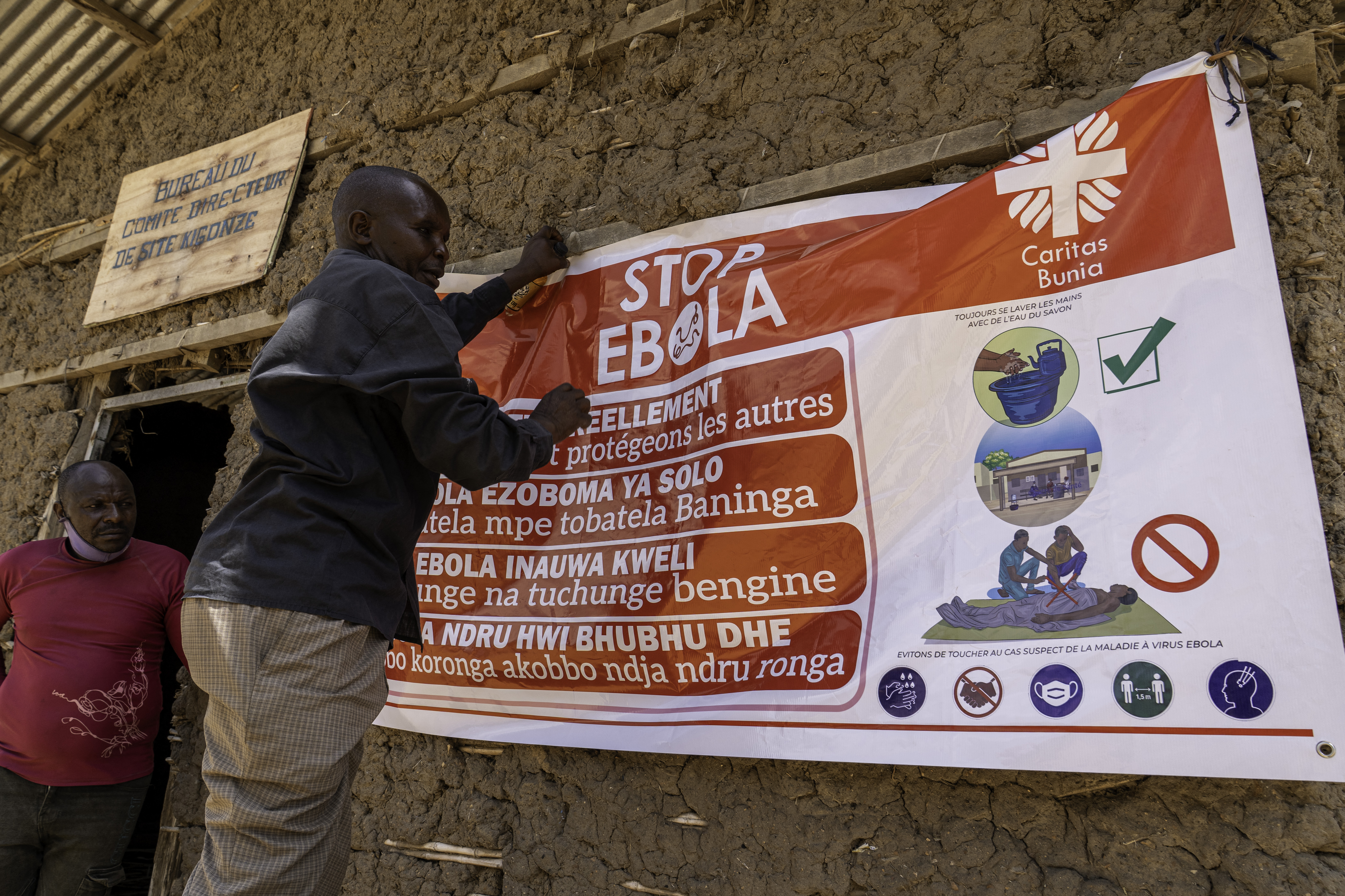 A man hangs an Ebola awareness banner.