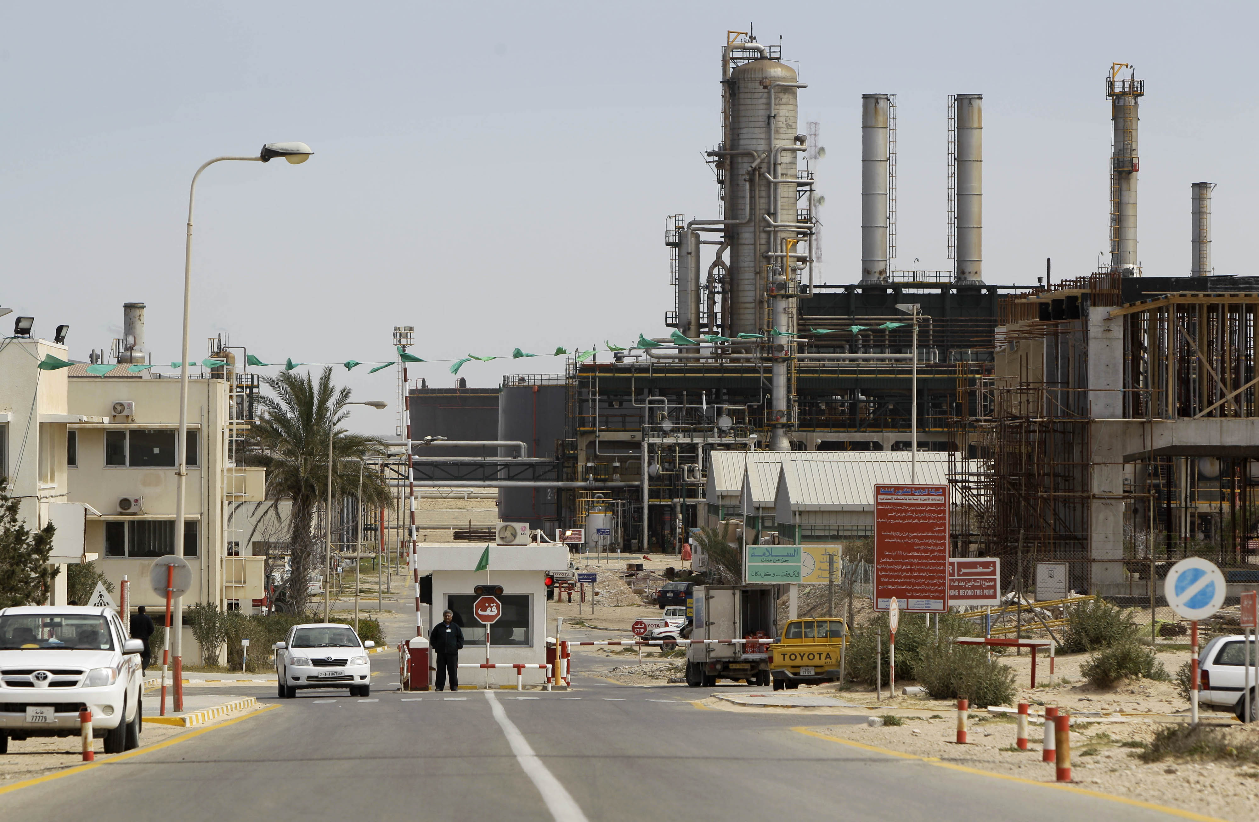 A security guard stands at at a gate inside the Zawiya Oil Refinery in Zawiya, west of Tripoli, Libya Thursday, March 3, 2011. Libya, which sits on the most reserves in Africa and is a major exporter to Europe, continues to produce oil, though experts say it's unclear how much will eventually make it to international ports. (AP Photo/Ben Curtis)
