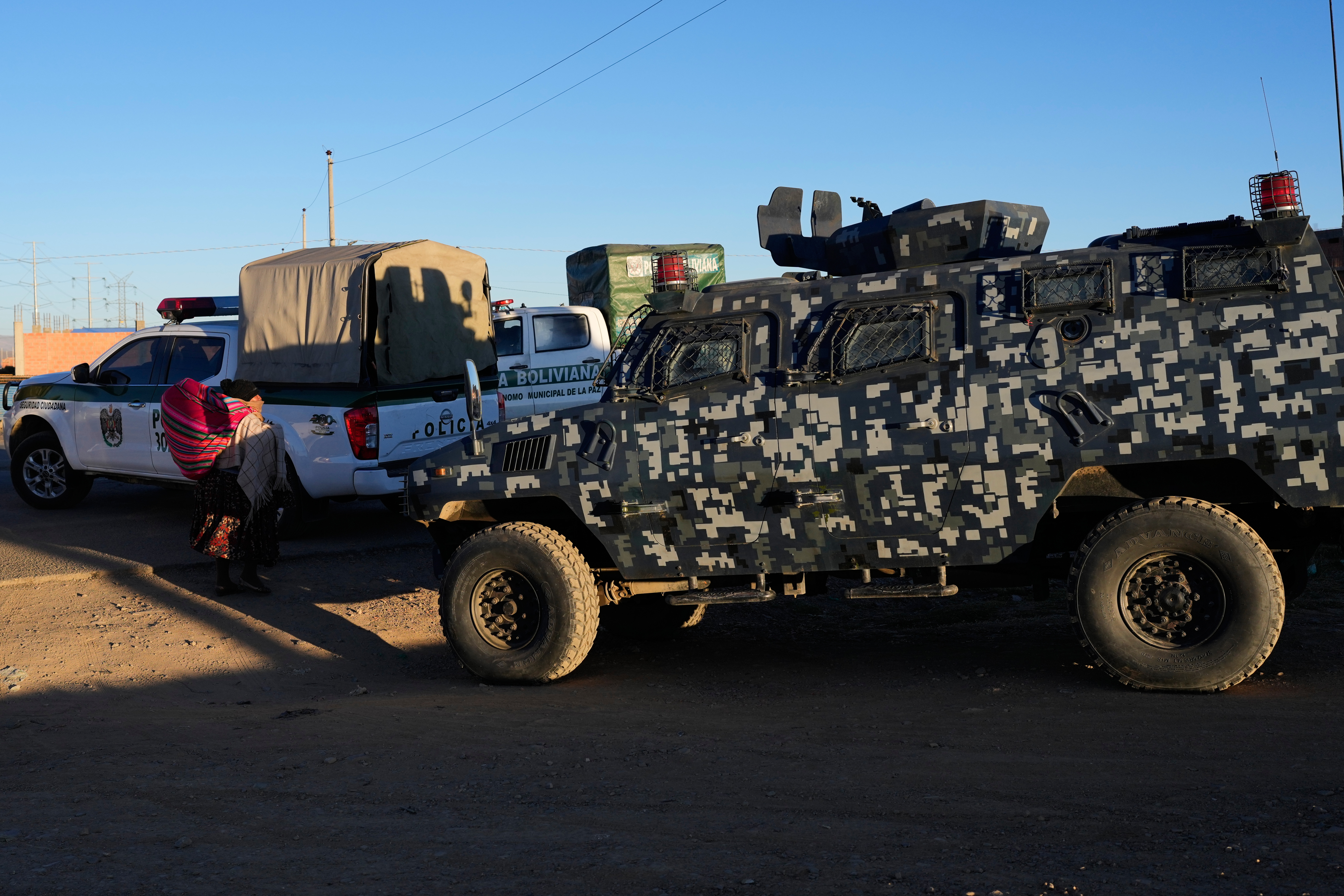 Police and army vehicles patrol a highway blocked by anti-government protesters near El Alto, Bolivia, Saturday, May 16, 2026, after protesters set up barricades. (AP Photo/Juan Karita)