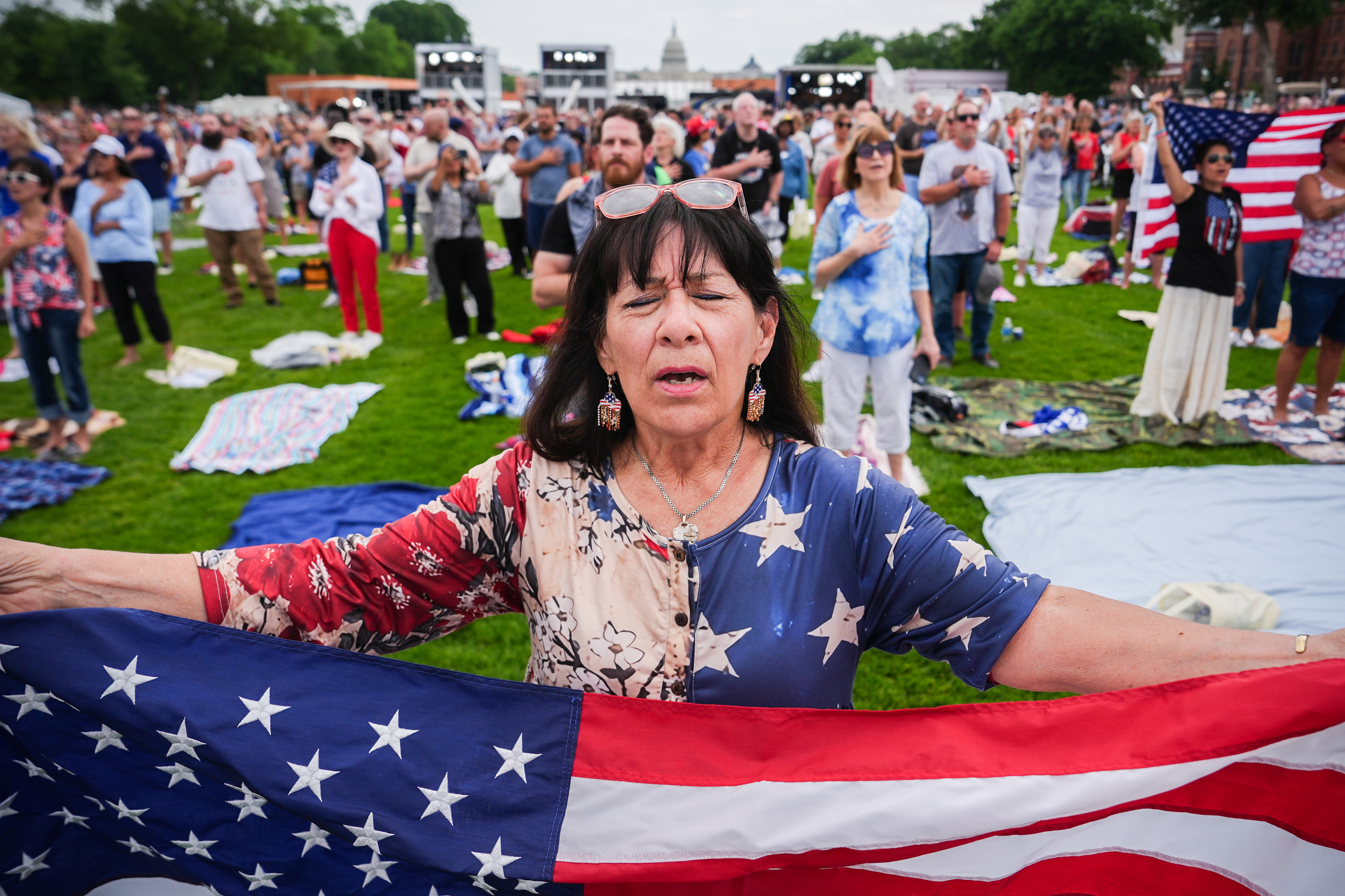 Kathy Fain, from Longview, Texas, holds an American flag while singing the National Anthem during Rededicate 250, a mostly conservative Christian prayer gathering in honor of the United States' 250th anniversary, on the National Mall, Sunday, May 17, 2026, in Washington. (AP Photo/Julia Demaree Nikhinson)